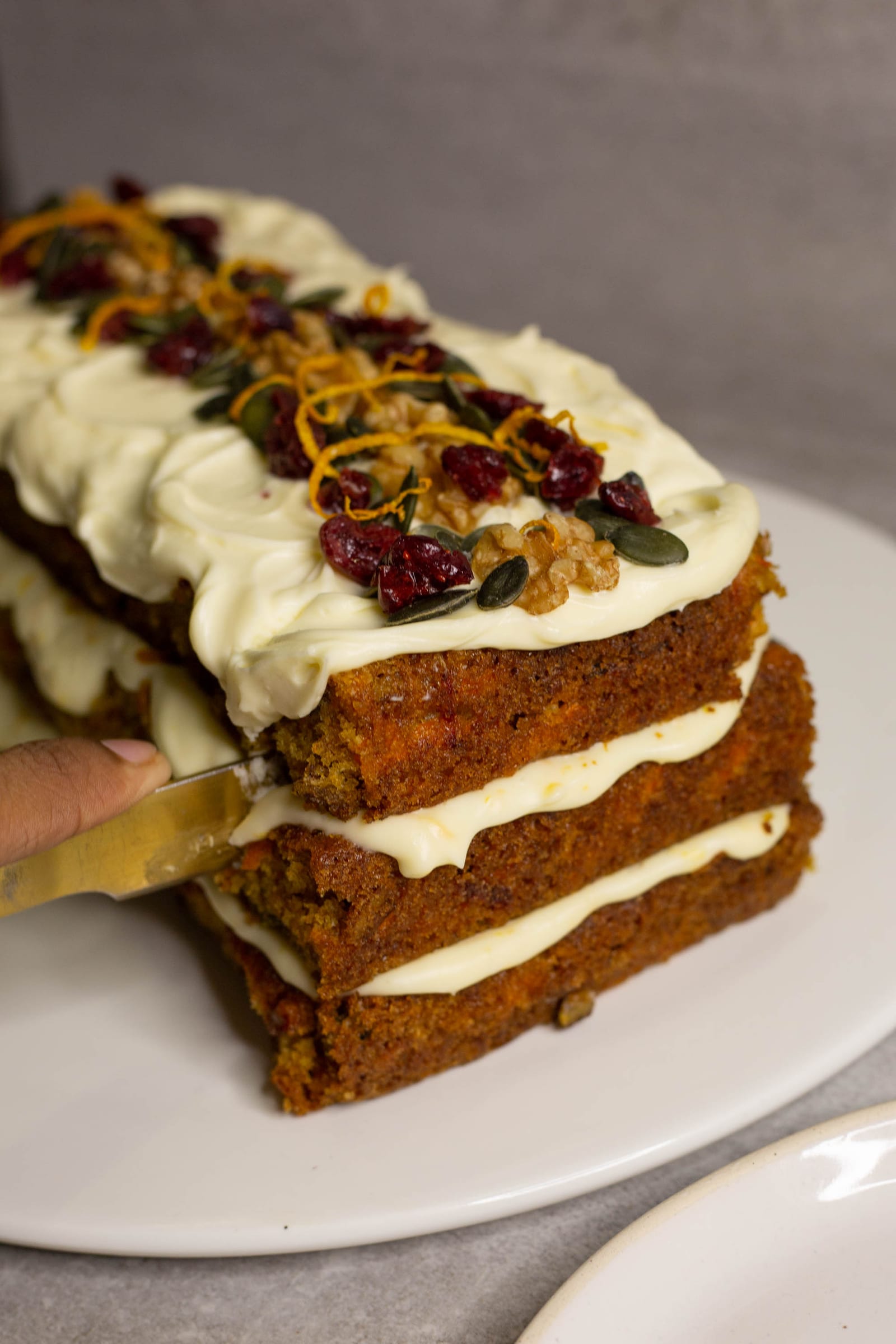A knife cutting a slice from the end of the carrot cake