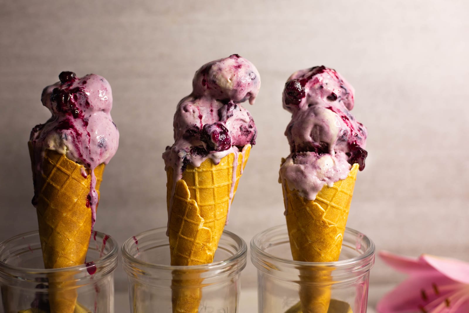 Three cones of blueberry swirl ice cream standing in glass jars