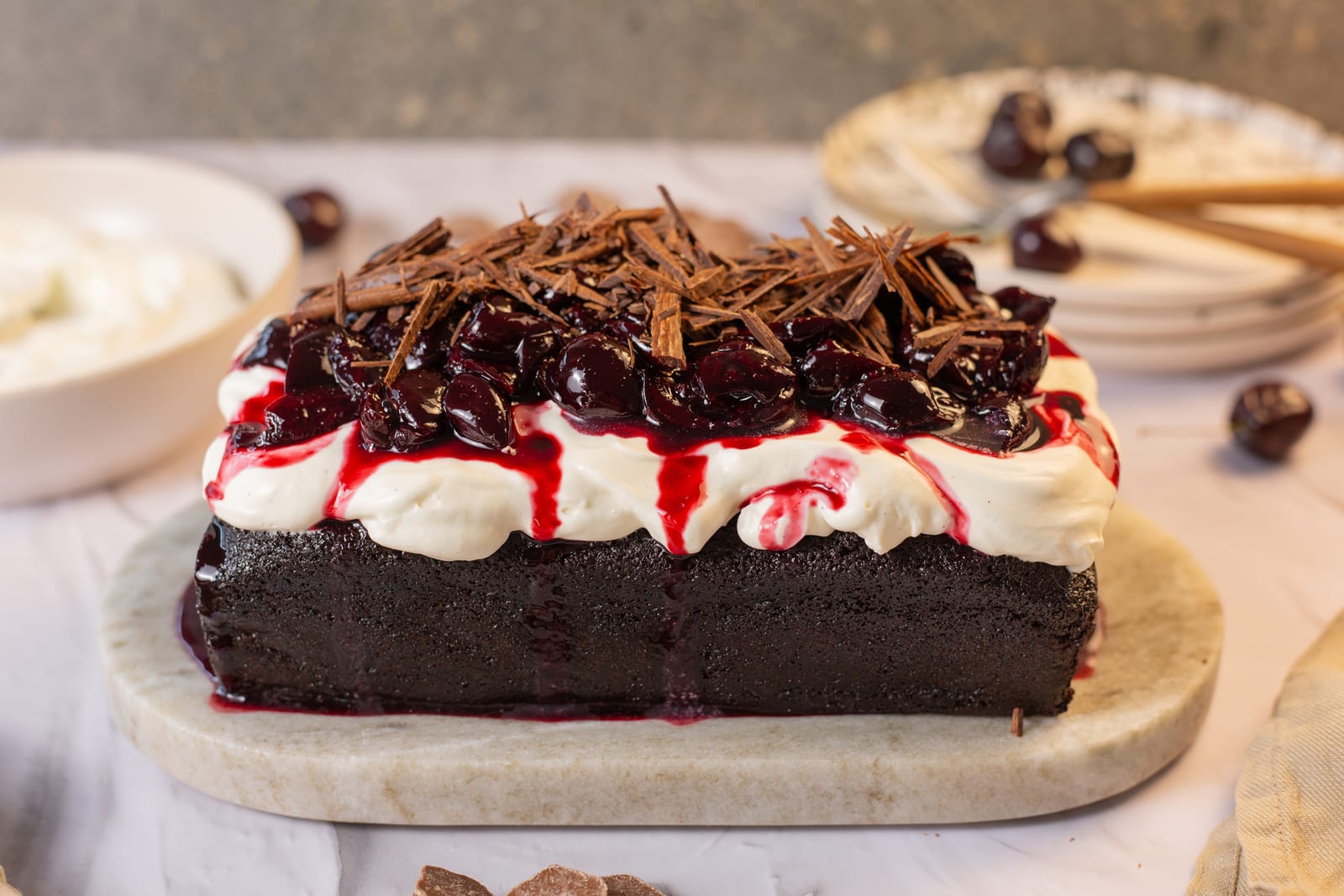 A black forest loaf topped with whipped cream, cherry compote and chocolate shavings