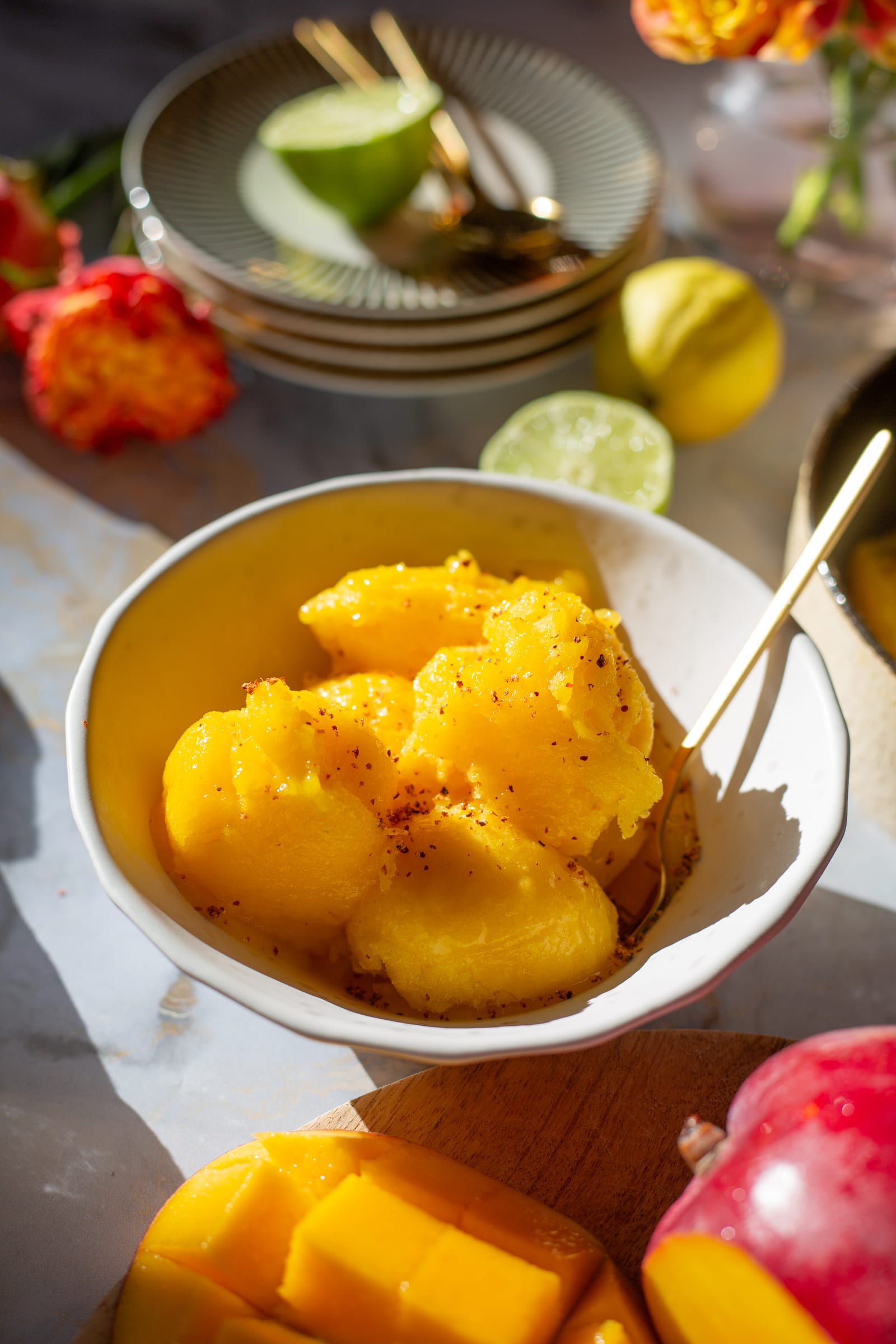 Scoops of mango and chilli sorbet in a white bowl dusted with chilli, at an angle