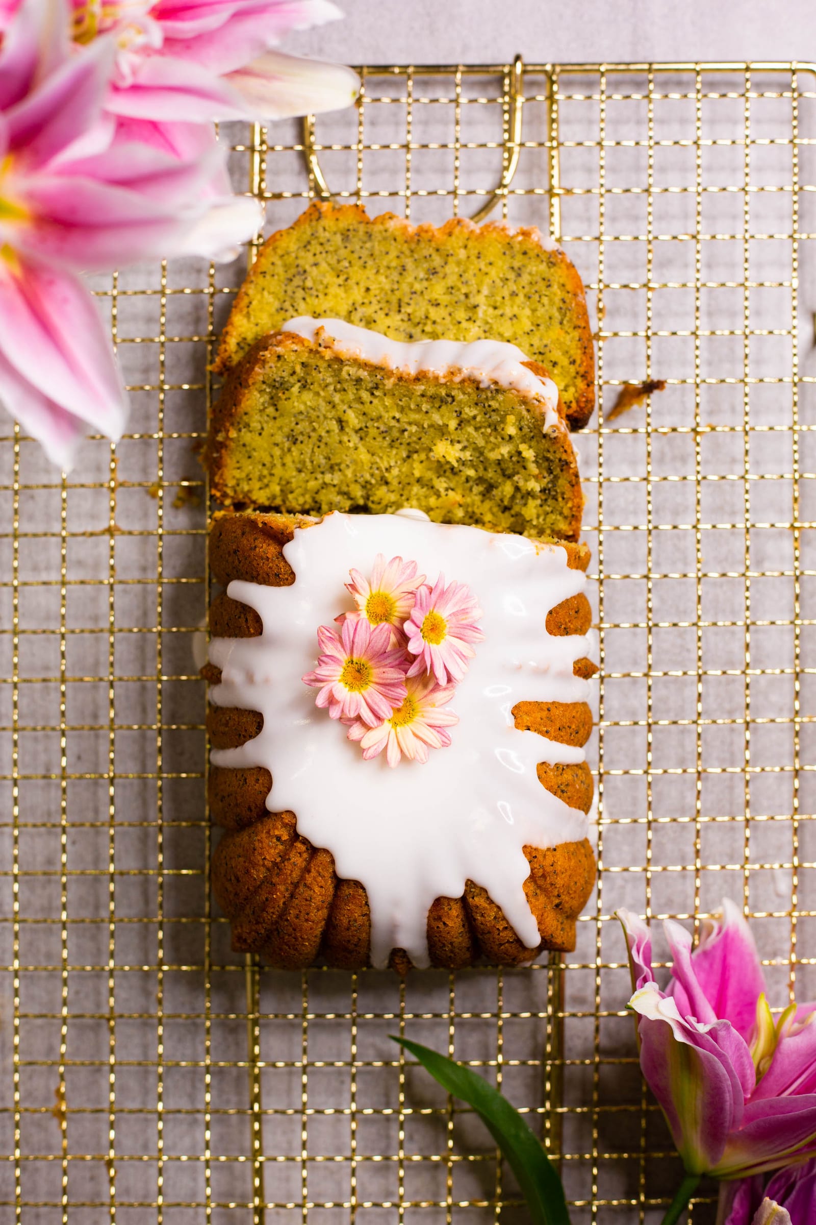 A cut gluten-free lemon and poppyseed loaf with slices laid beside it, from above