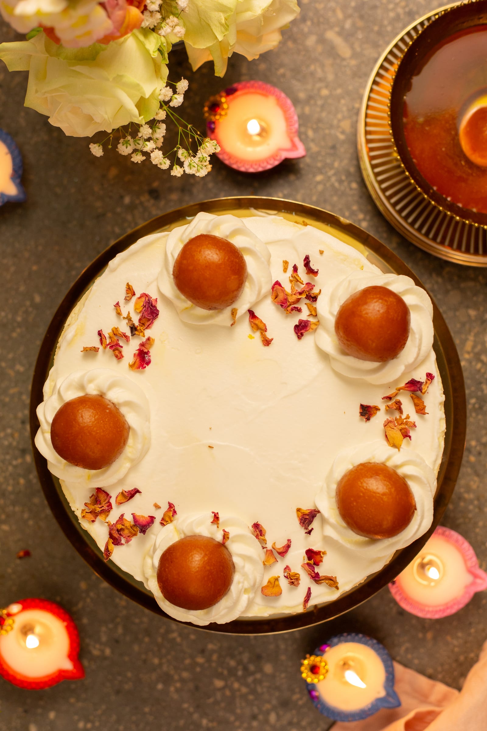 The gulab jamun cheesecake from above, with rose petals and diyas