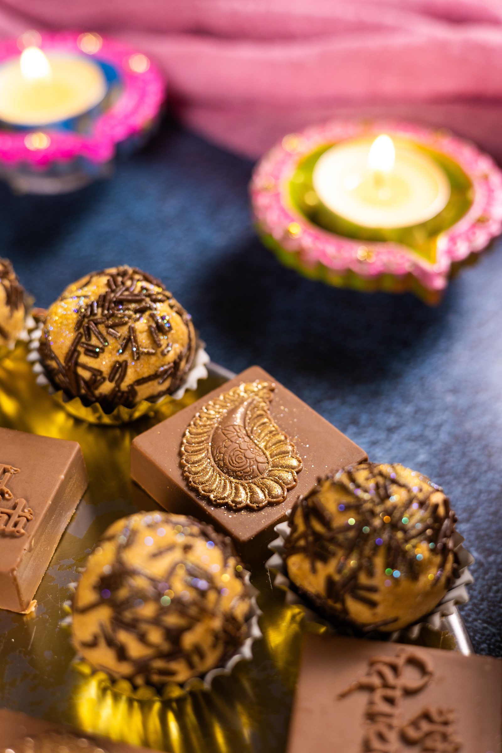 Close-up of round caramel Simply Wonderfuls topped with chocolate, beside a square one with a gold paisley