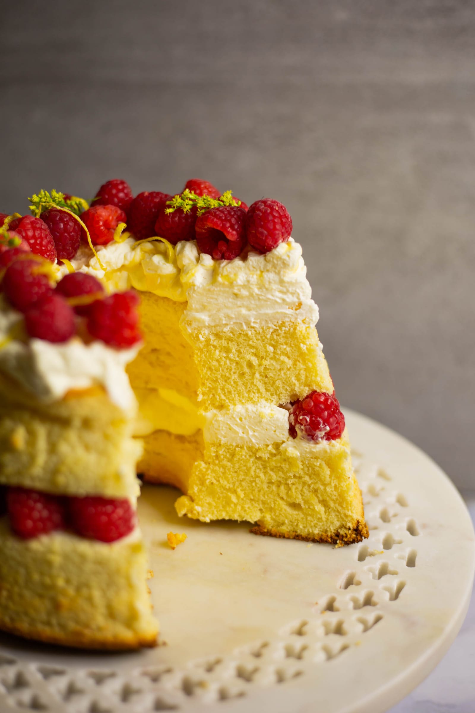 A lemon curd and raspberry chiffon cake with a wedge cut out, showing the airy crumb