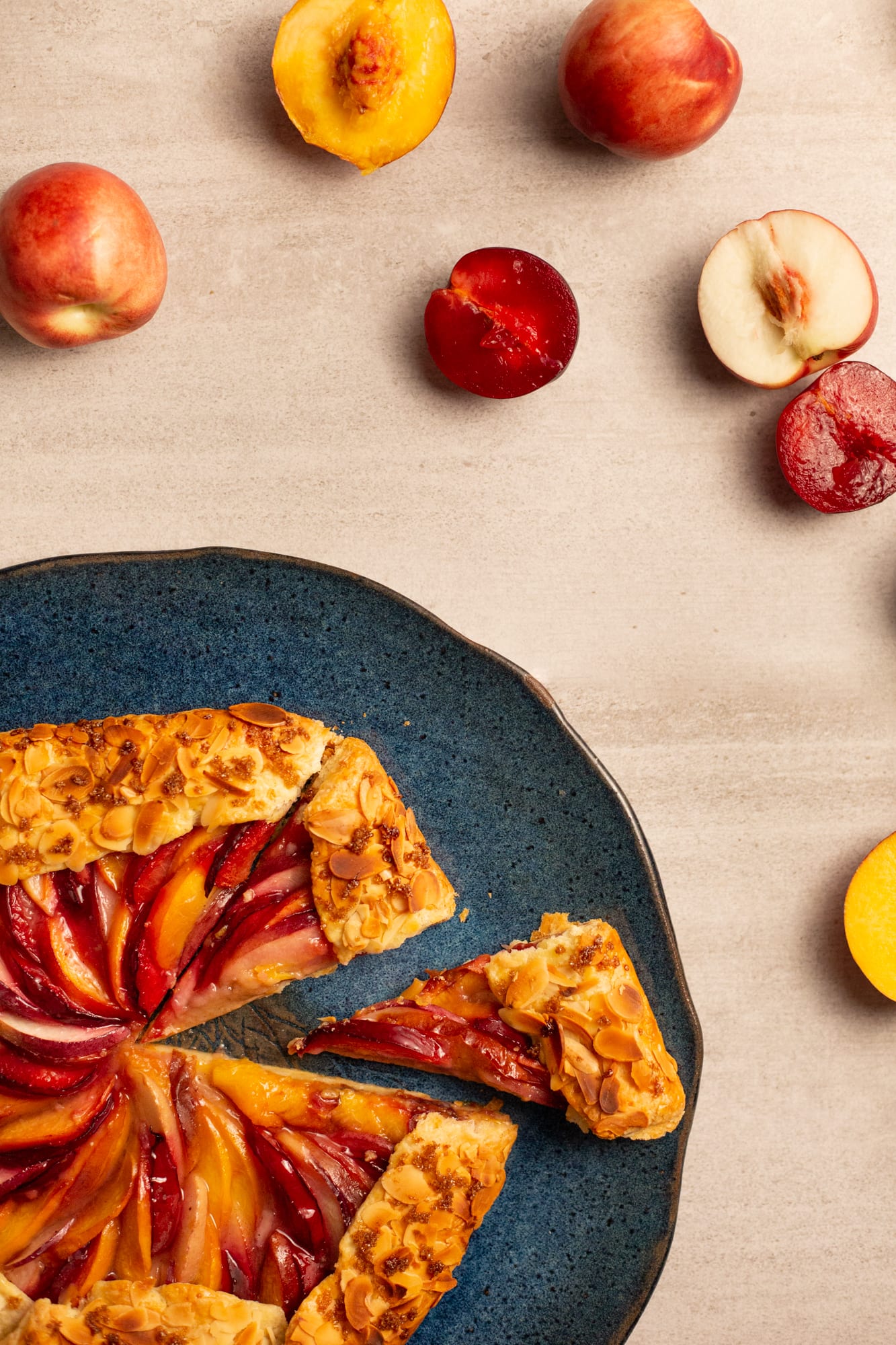 A stone fruit galette cut into wedges on a teal plate, from above