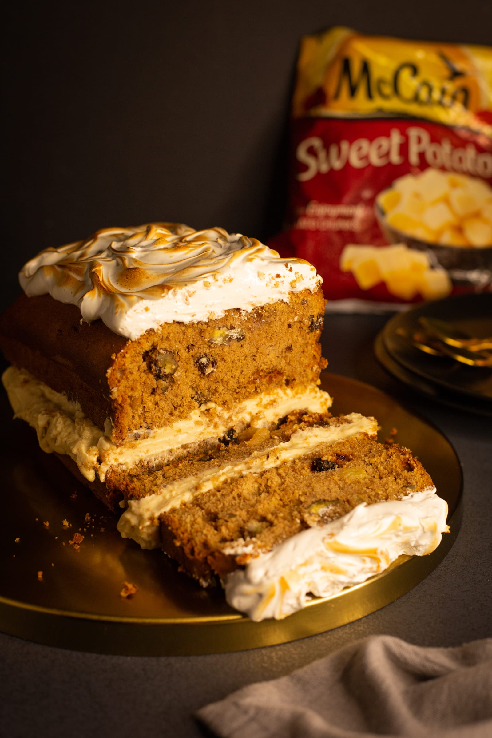 Slices of sweet potato loaf fanned out in front of the loaf on a gold board