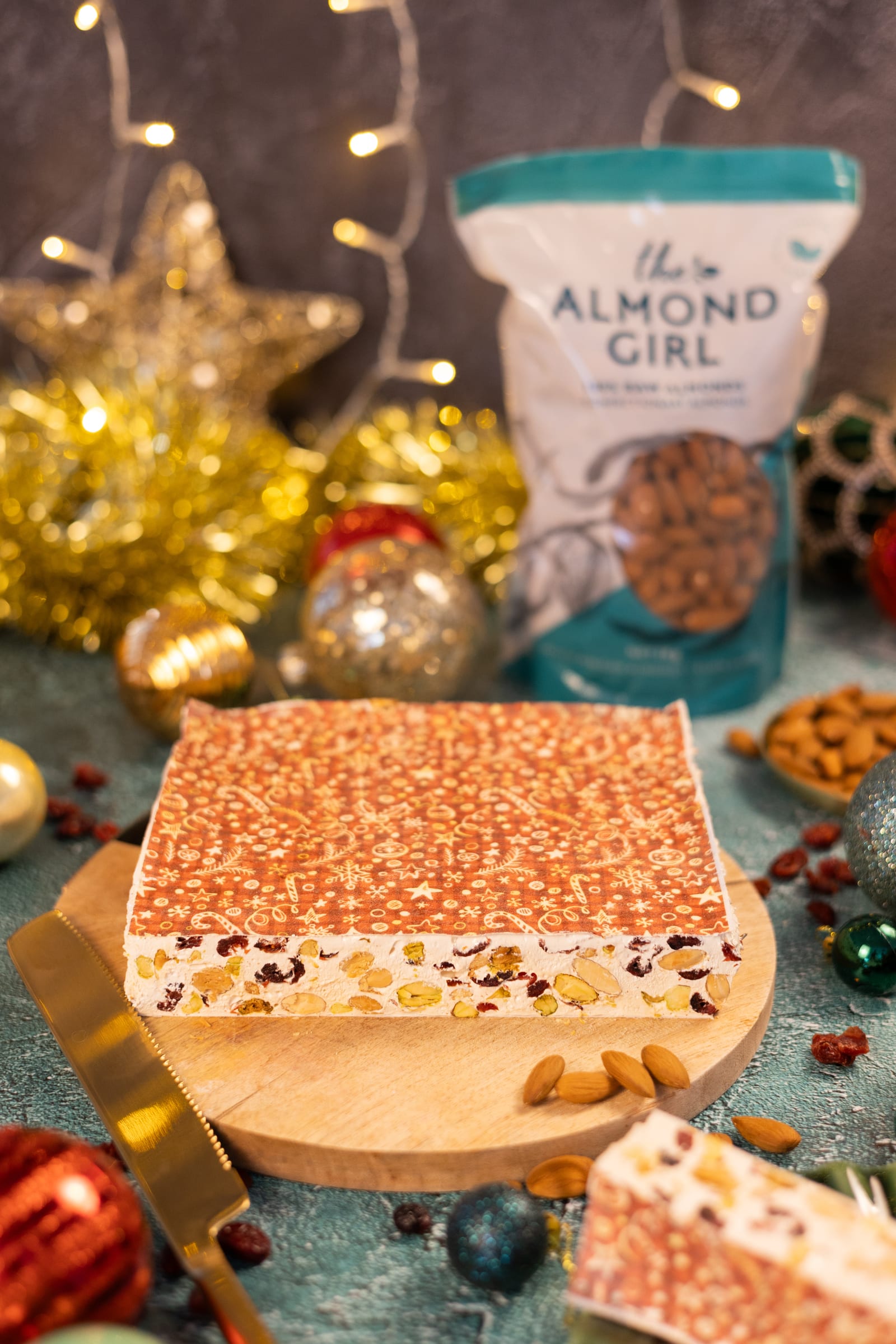 A slab of nougat on a wooden board, beside a bag of almonds