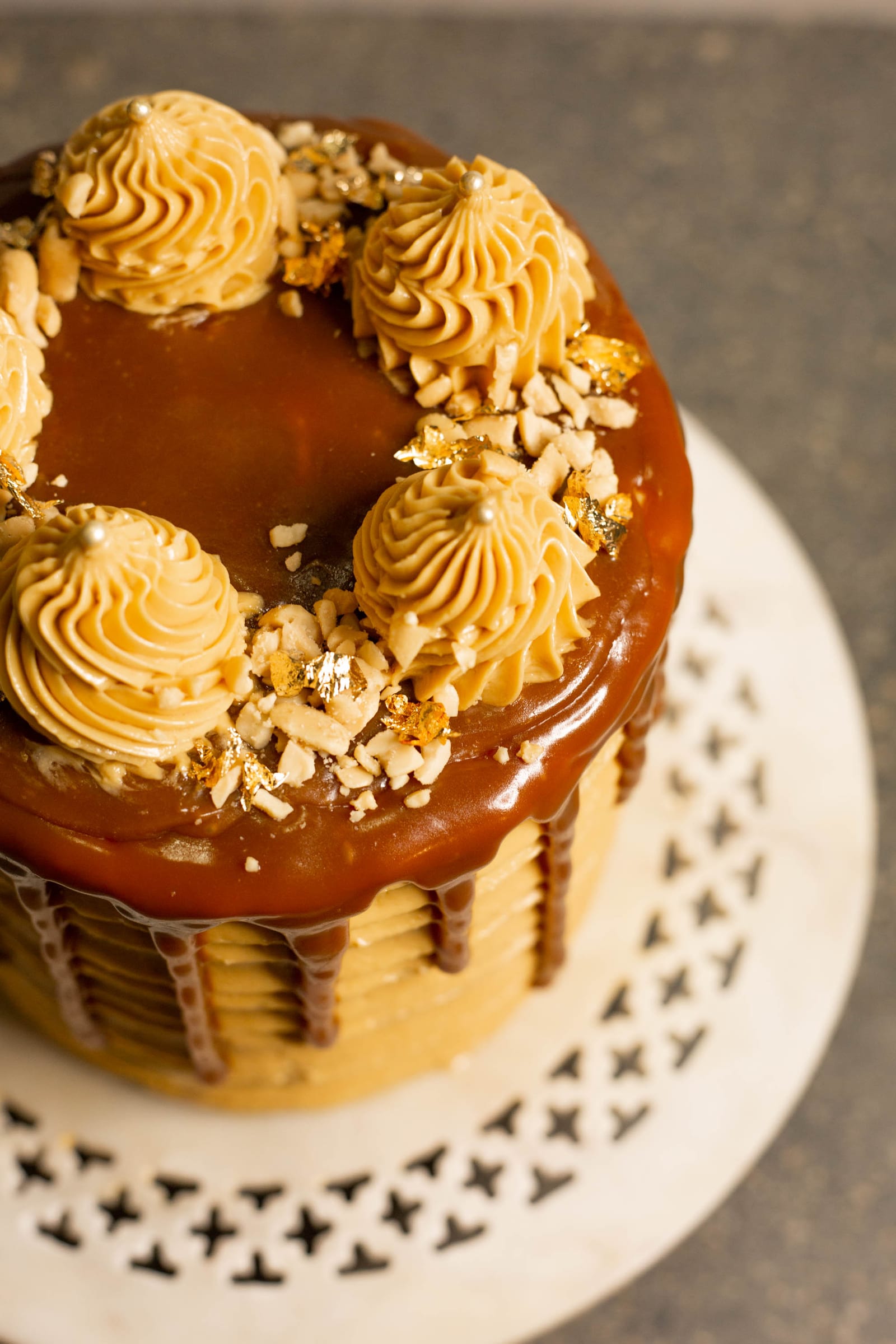 Close-up of the caramel, rosettes and peanuts on top of a salted caramel peanut cake