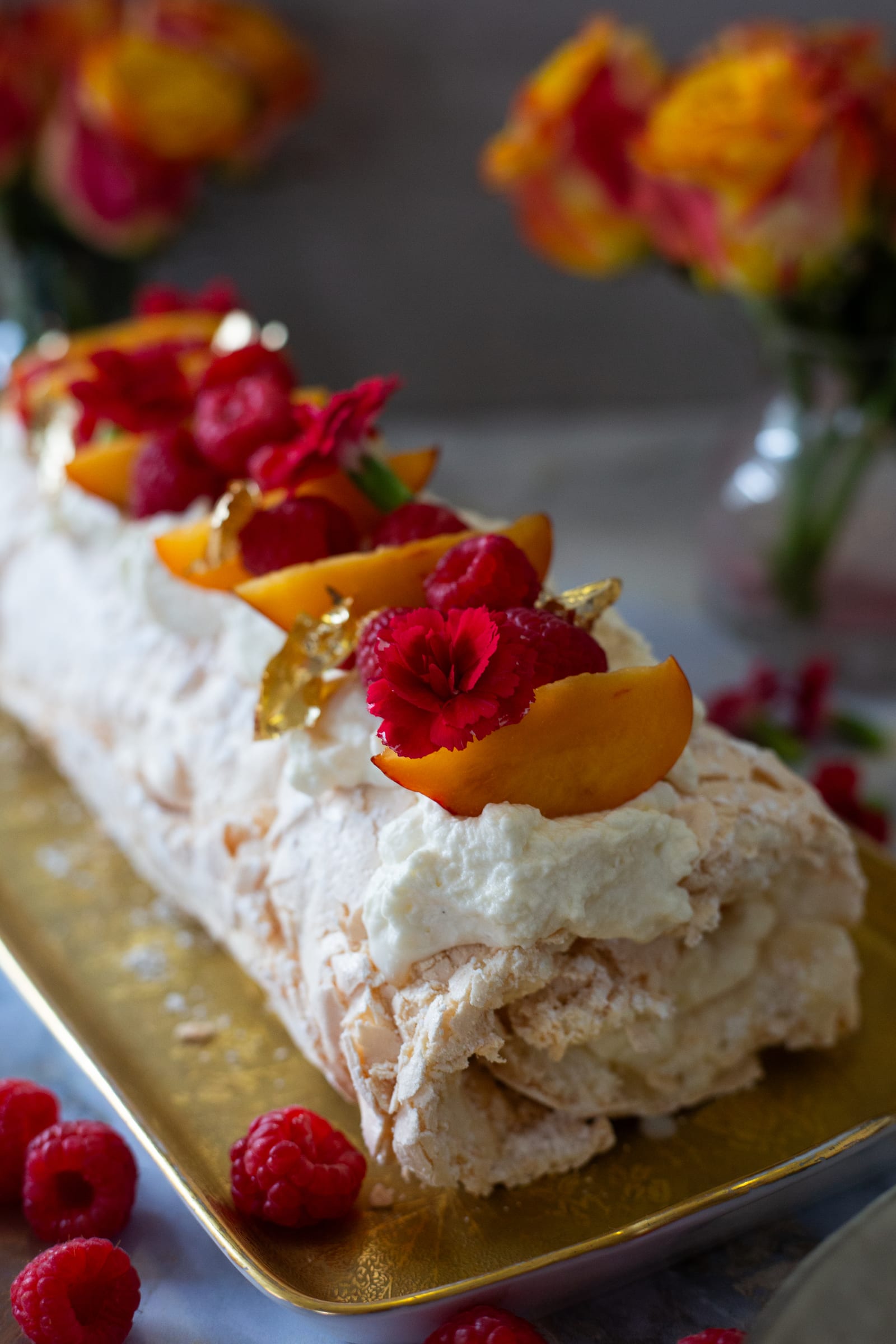 The end of the roulade with whipped cream, raspberries, nectarine and flecks of gold leaf