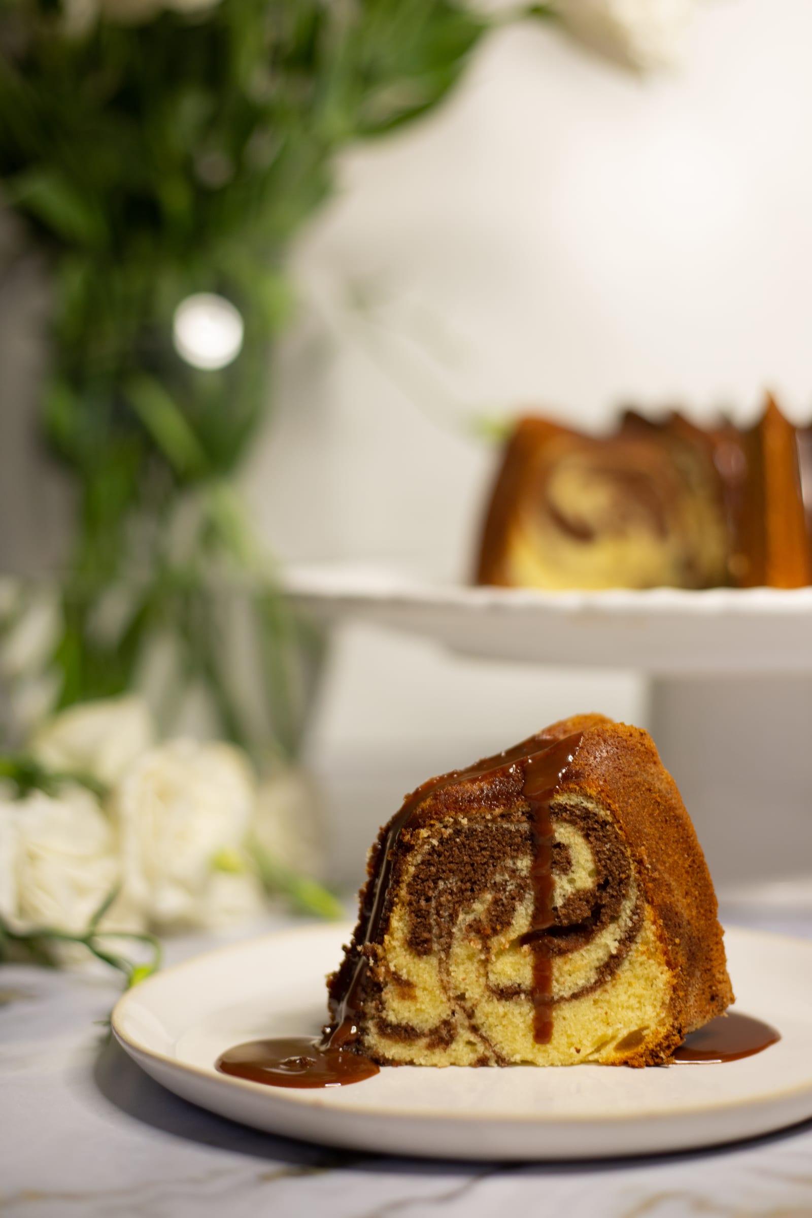 A slice of marble pound cake with chocolate ganache on a small plate