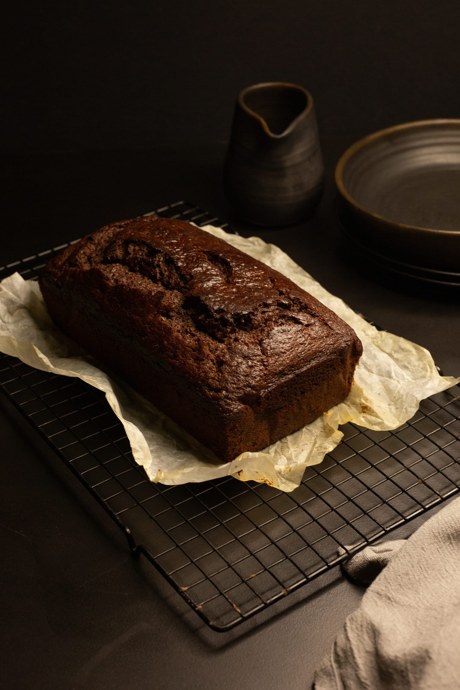 An unglazed chocolate banana bread cooling on baking paper and a wire rack