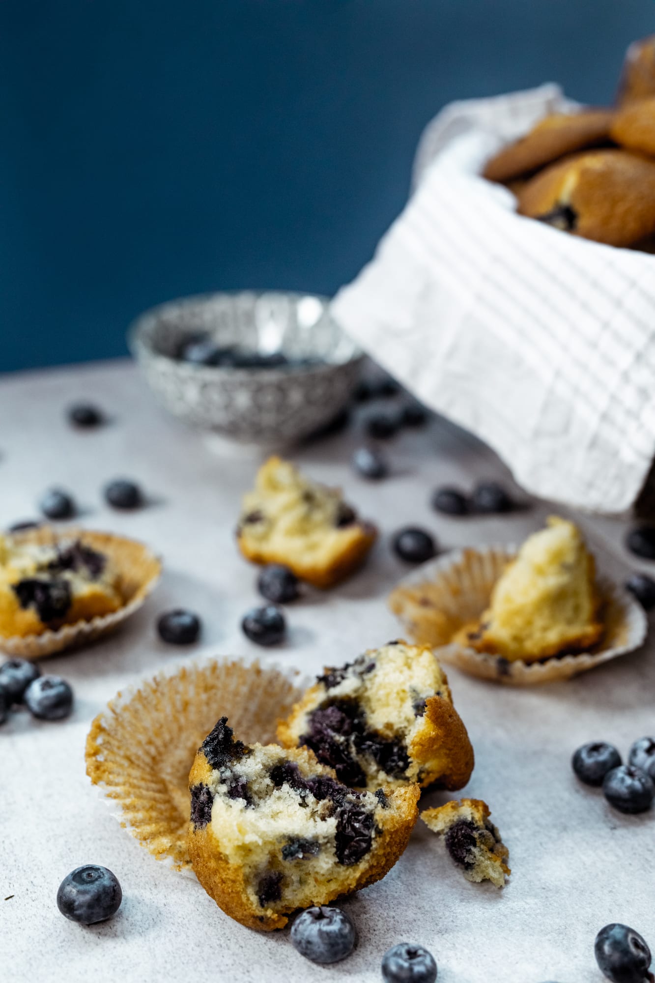 One bowl blueberry muffins broken open in front of the basket