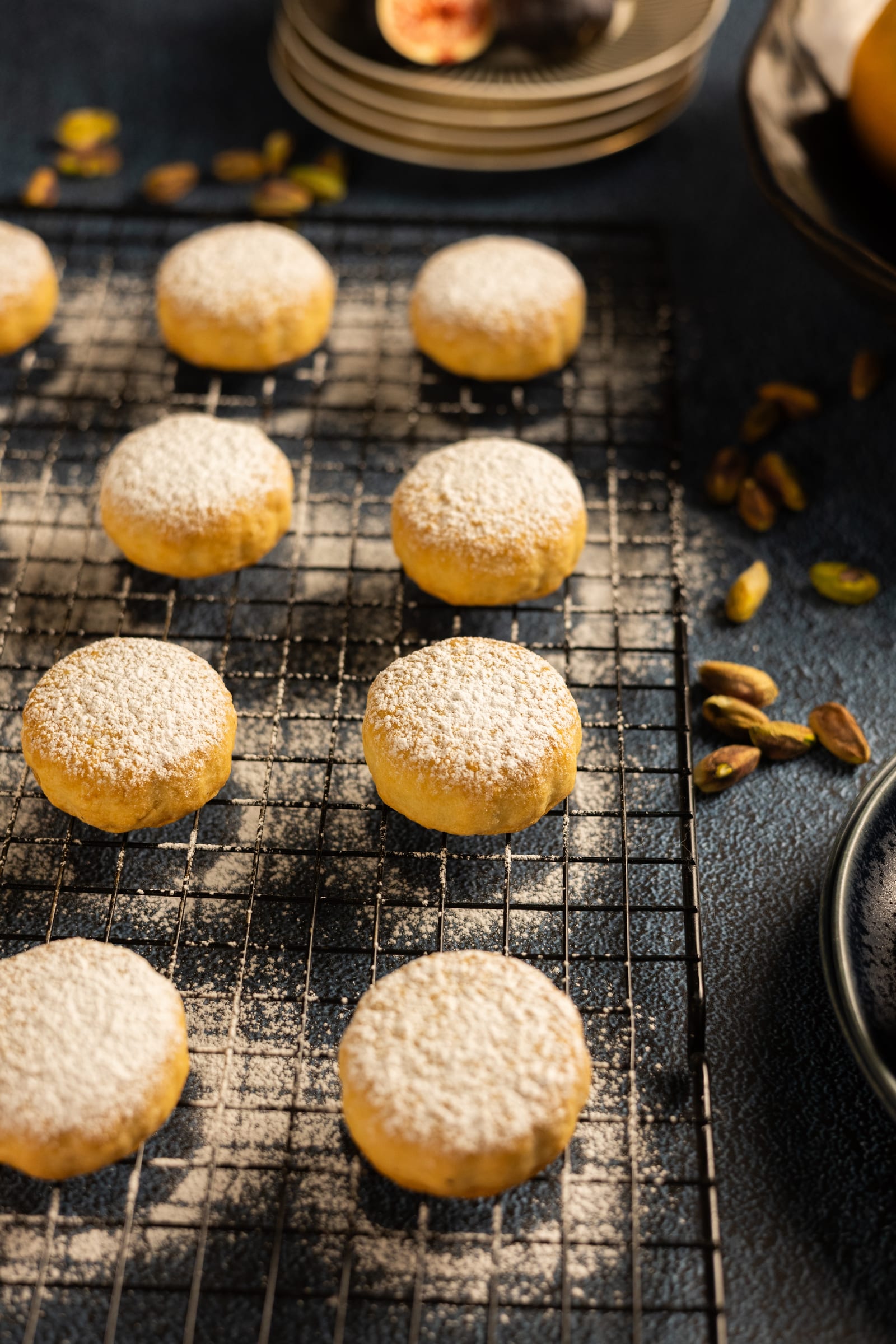 Baked ma'amoul dusted with icing sugar on a wire rack