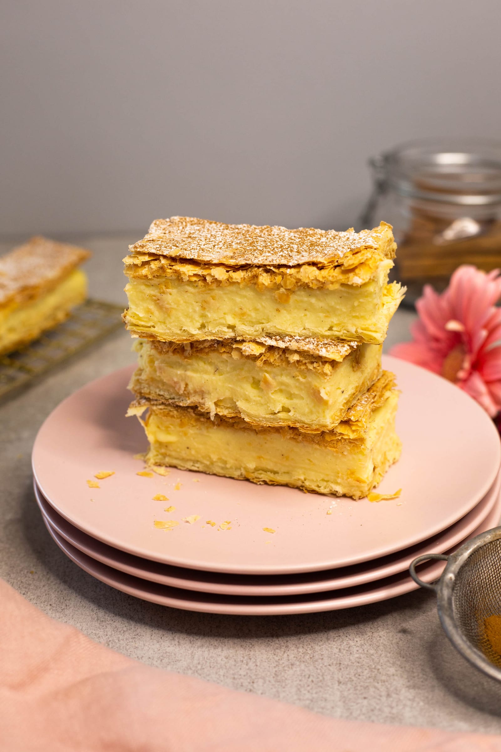 Three milk tart slices stacked on pink plates, from the side