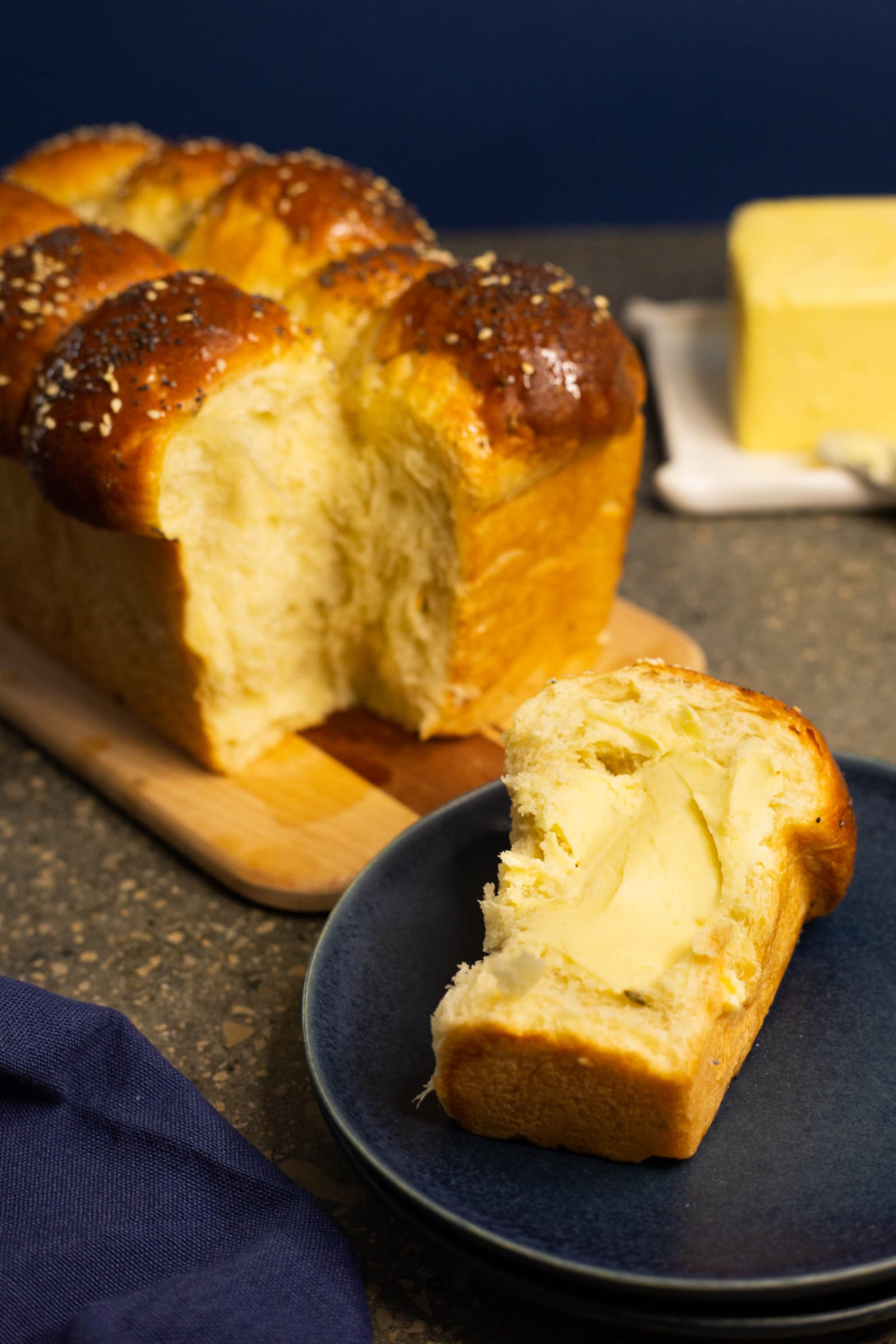 A torn-open mosbolletjie with a buttered piece on a blue plate