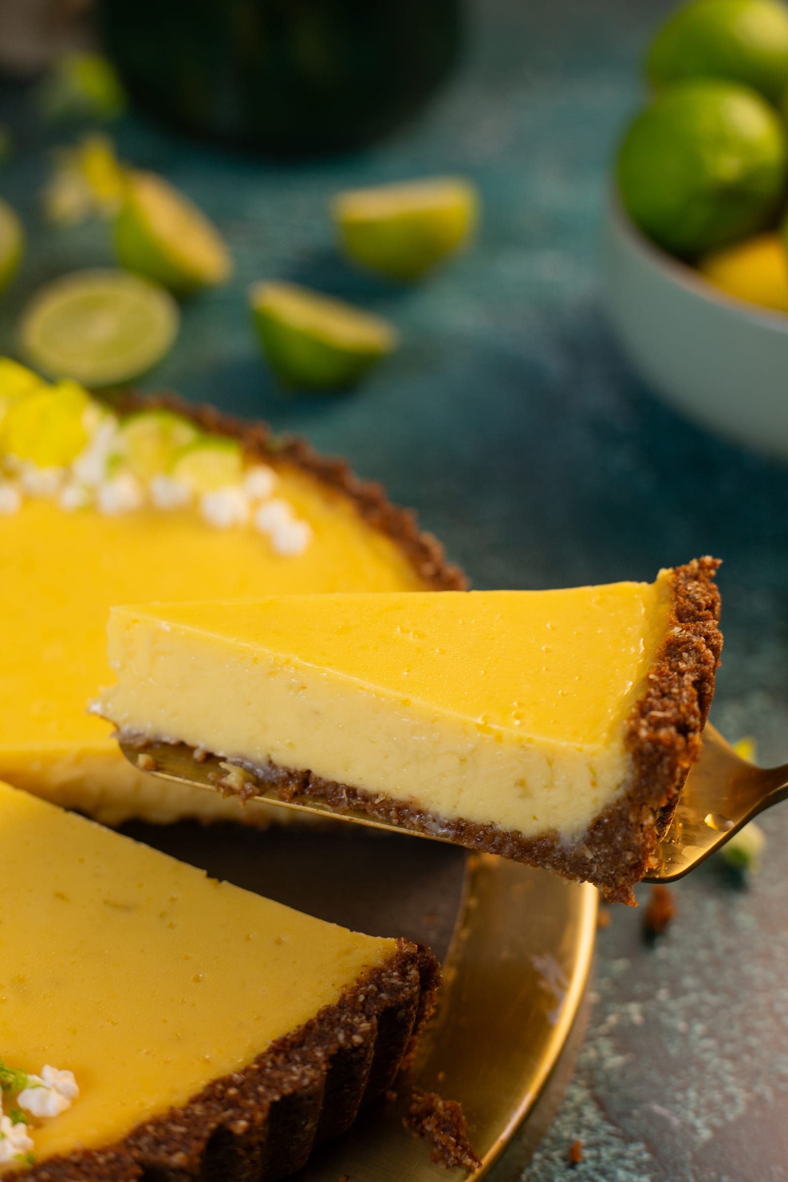 A slice of key lime pie being lifted out, showing the ginger crust