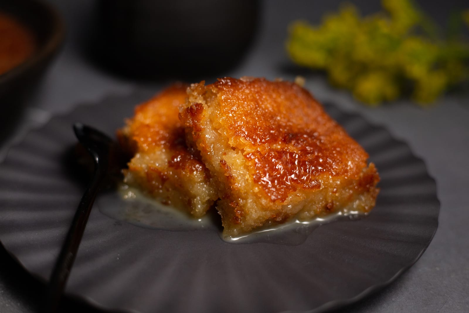 Close-up of a square of malva pudding on a dark plate
