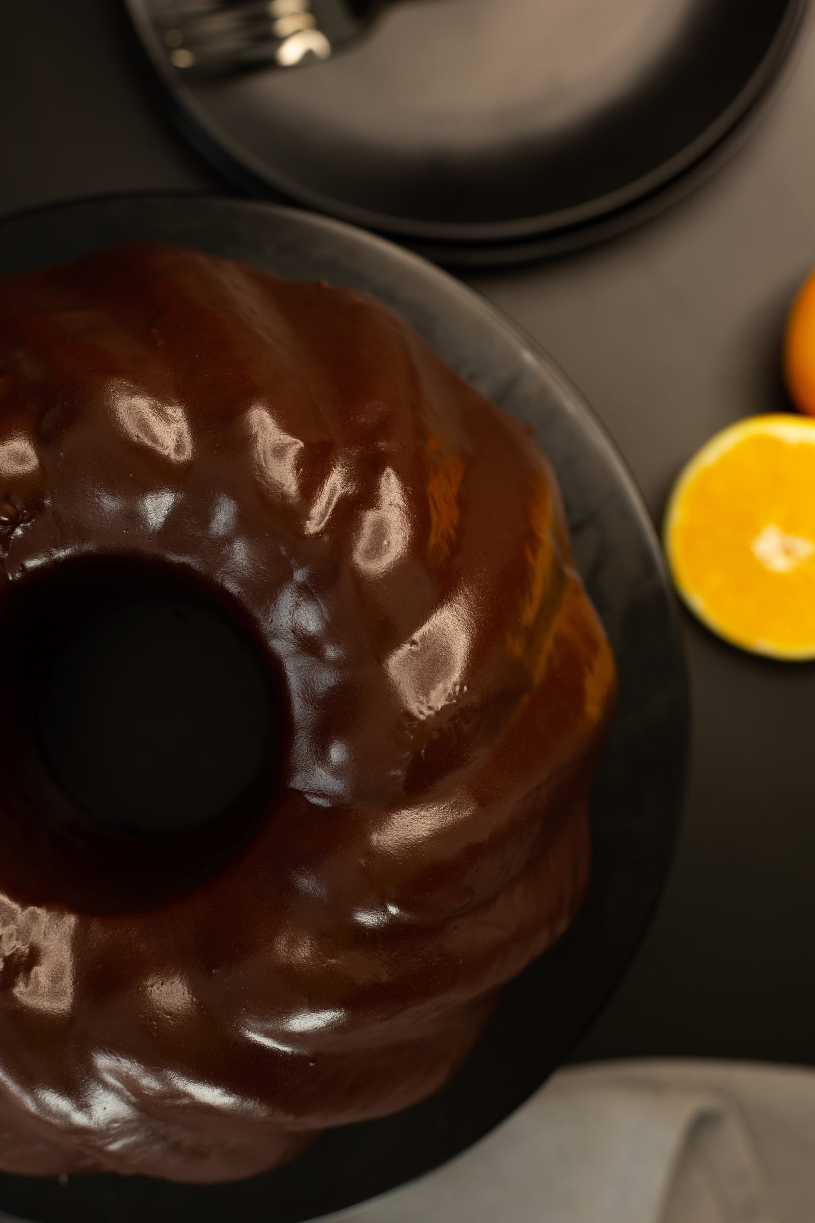 The dark chocolate glaze over the bundt from above, beside an orange half