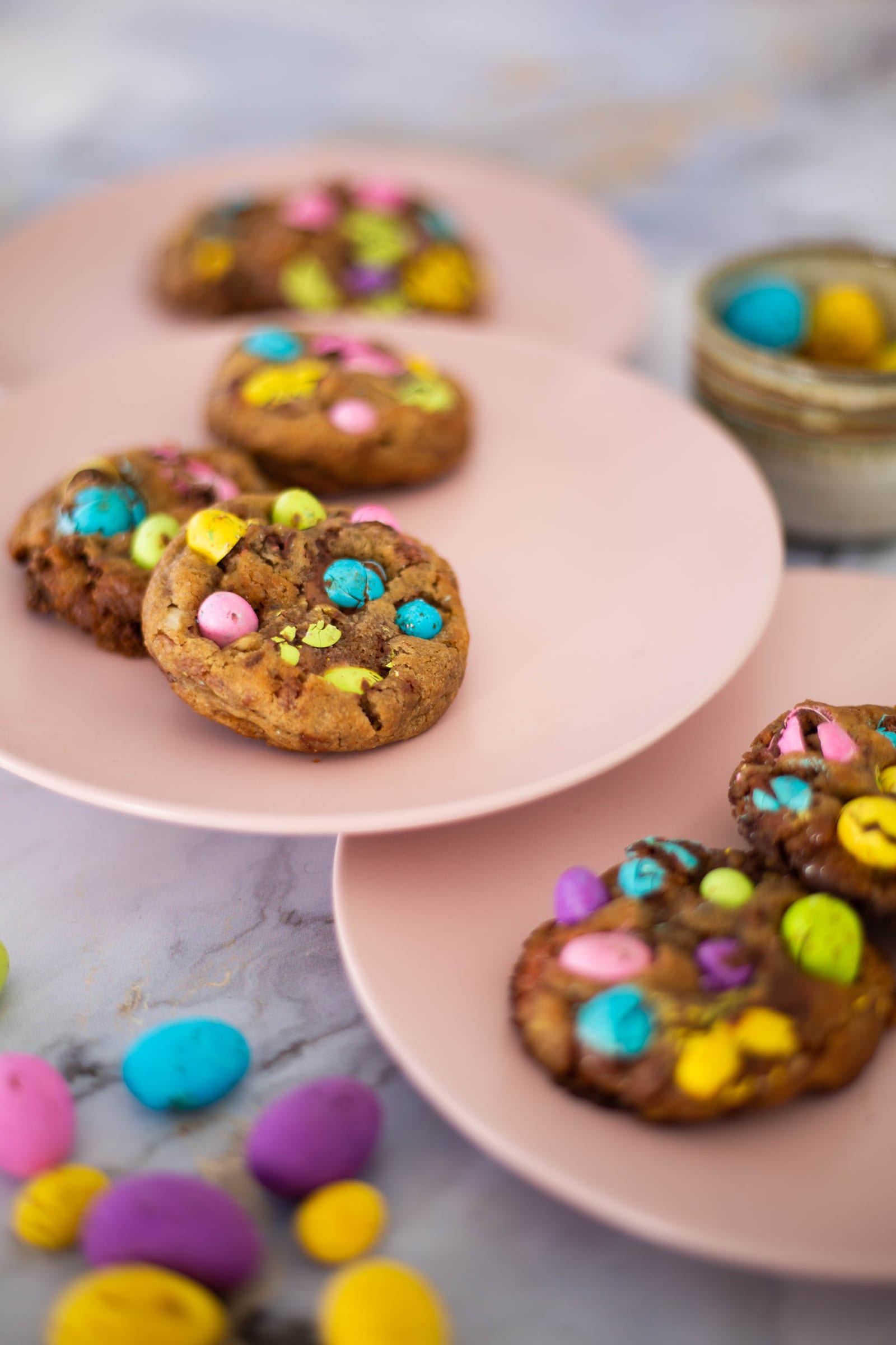 Speckled egg choc chunk cookies on pink plates, speckled eggs in front