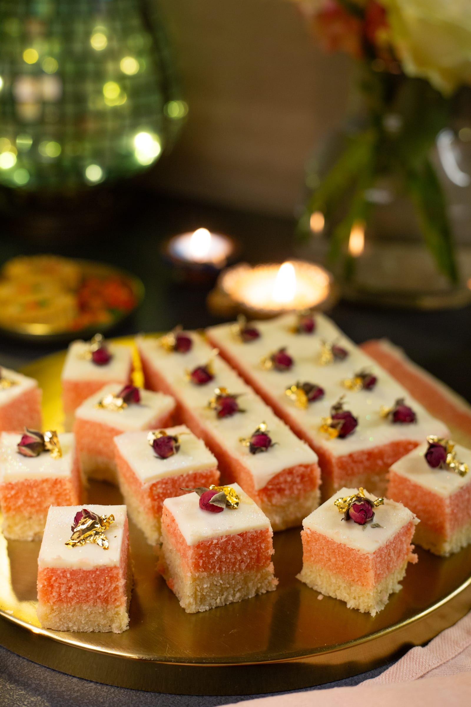 Kopra paak cubes and a slab on a gold plate beside a mosaic lantern and flowers