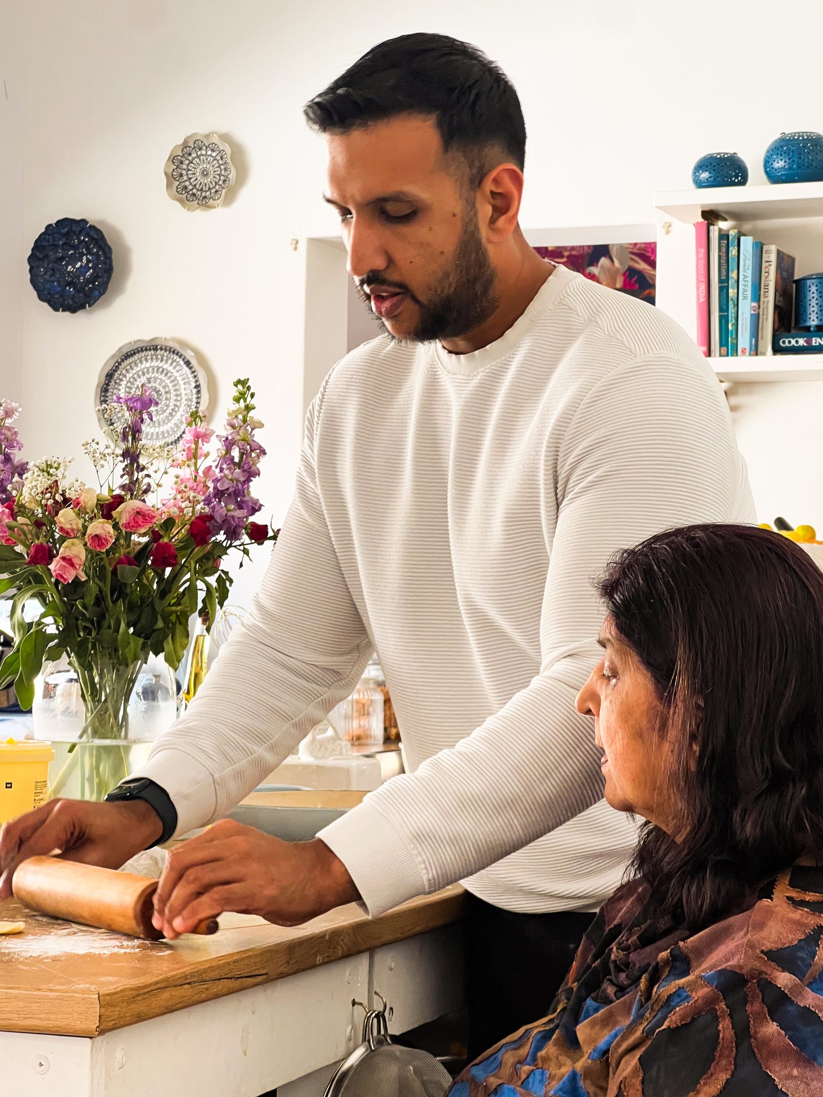 Rolling out the mawa ghari pastry at the kitchen counter, with a woman seated alongside