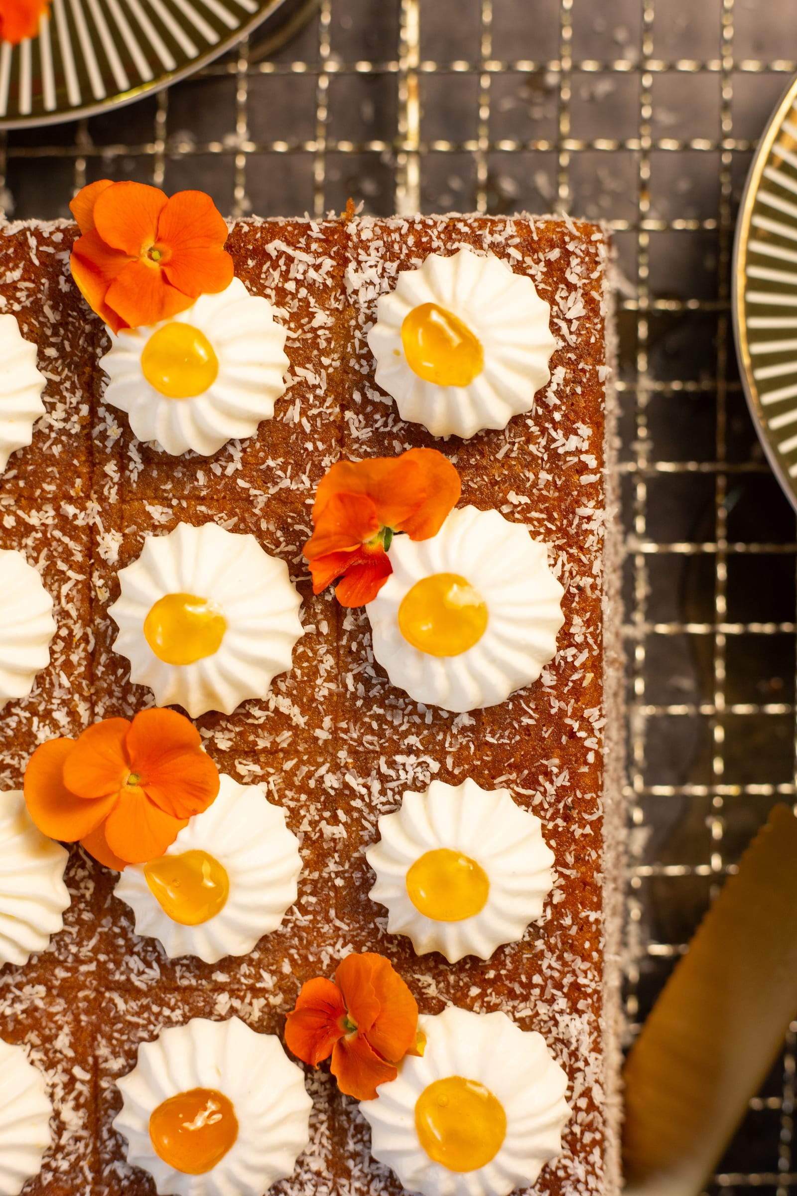 Close-up of cream rosettes and orange flowers on the traybake
