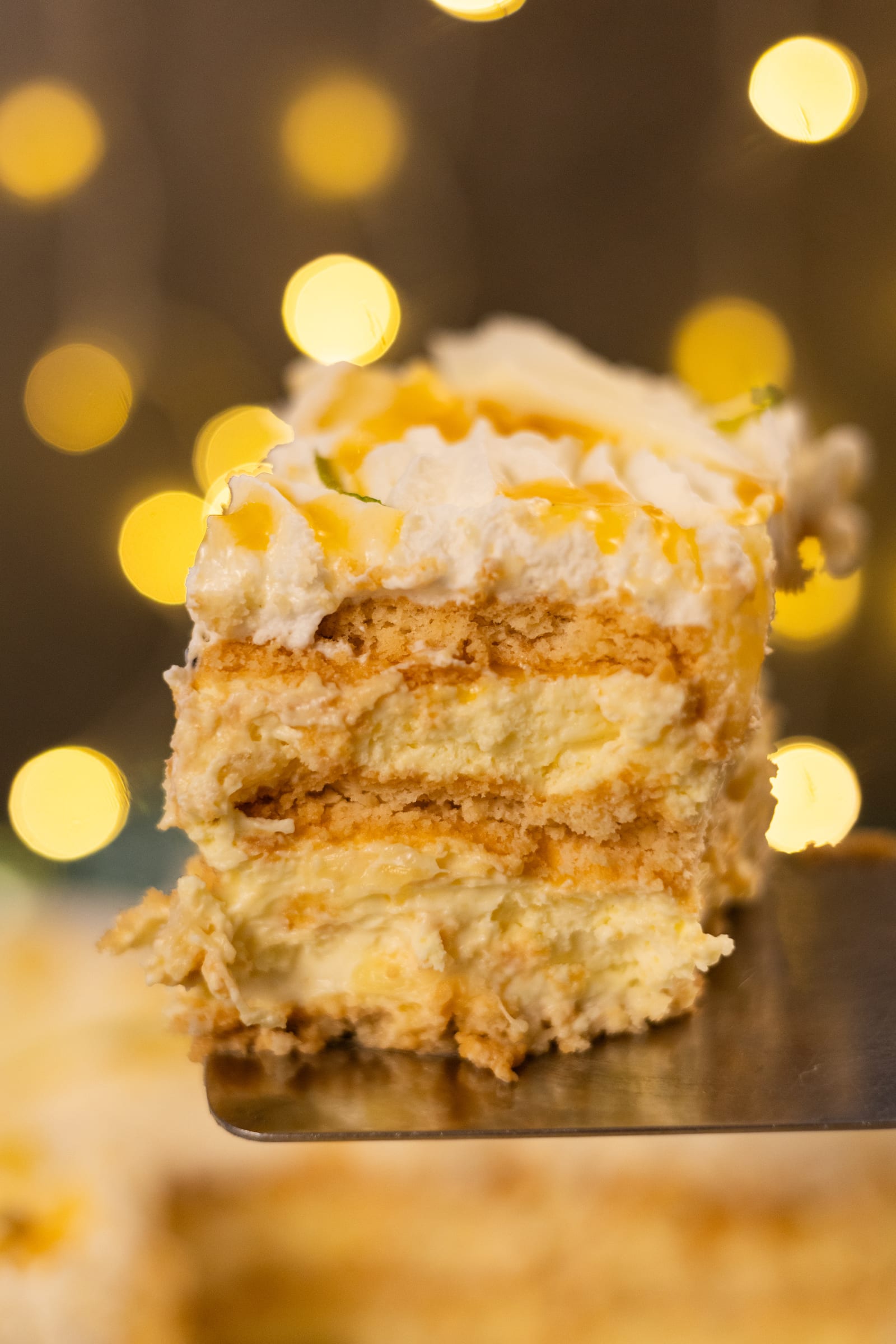 A slice of fridge tart lifted out, showing the biscuit and pineapple layers
