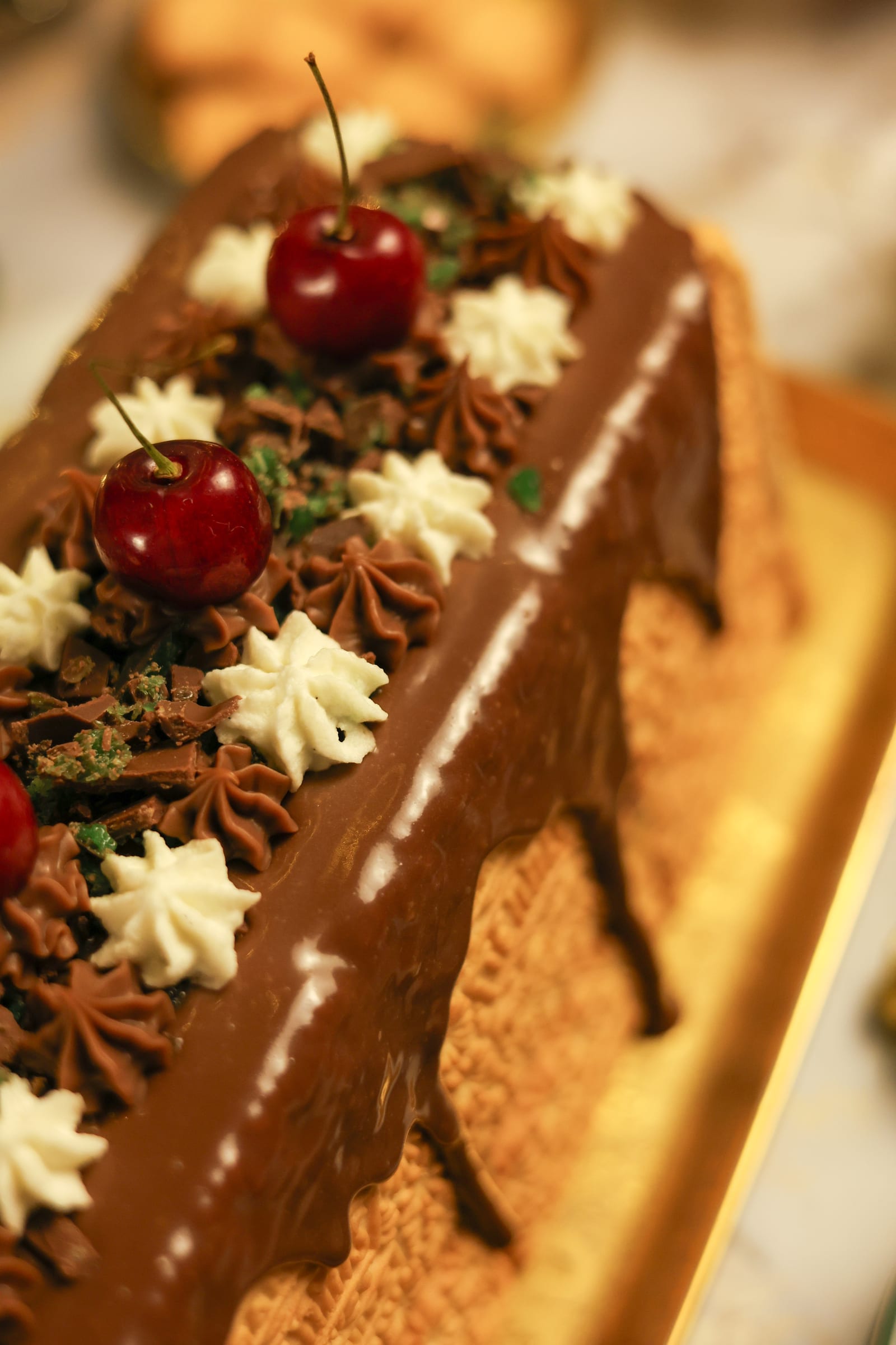 Close-up of piped cream, cherries and chocolate on top of the loaf