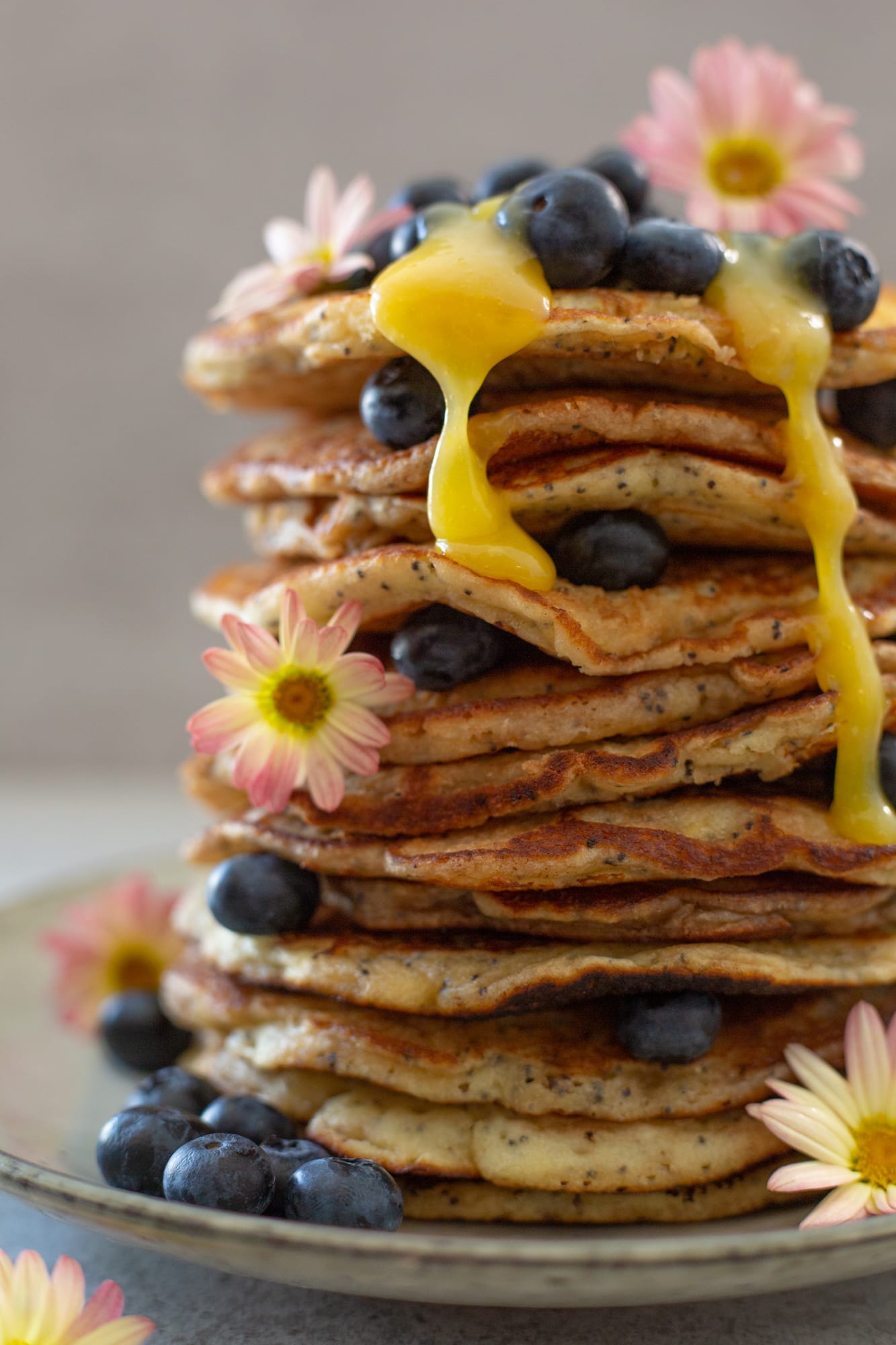 Close-up of lemon curd running down a stack of lemon and poppyseed pancakes
