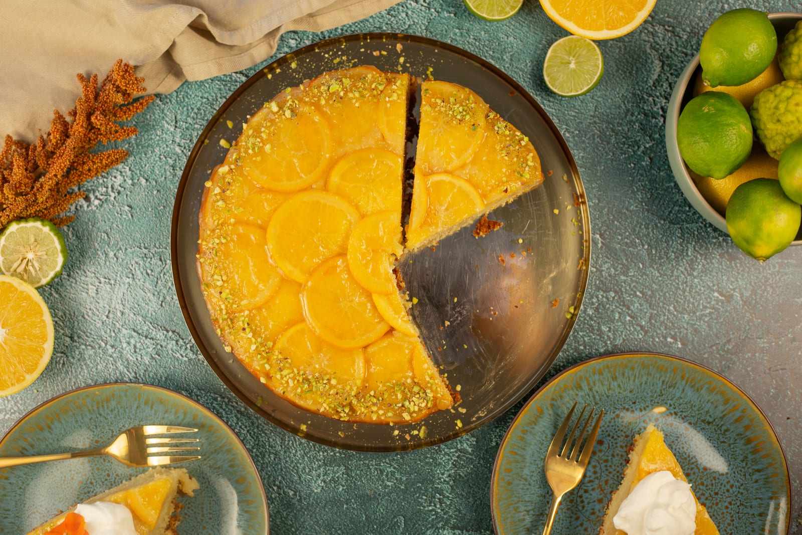 The orange and olive oil upside down cake with a wedge cut out, and a slice on a plate beside it