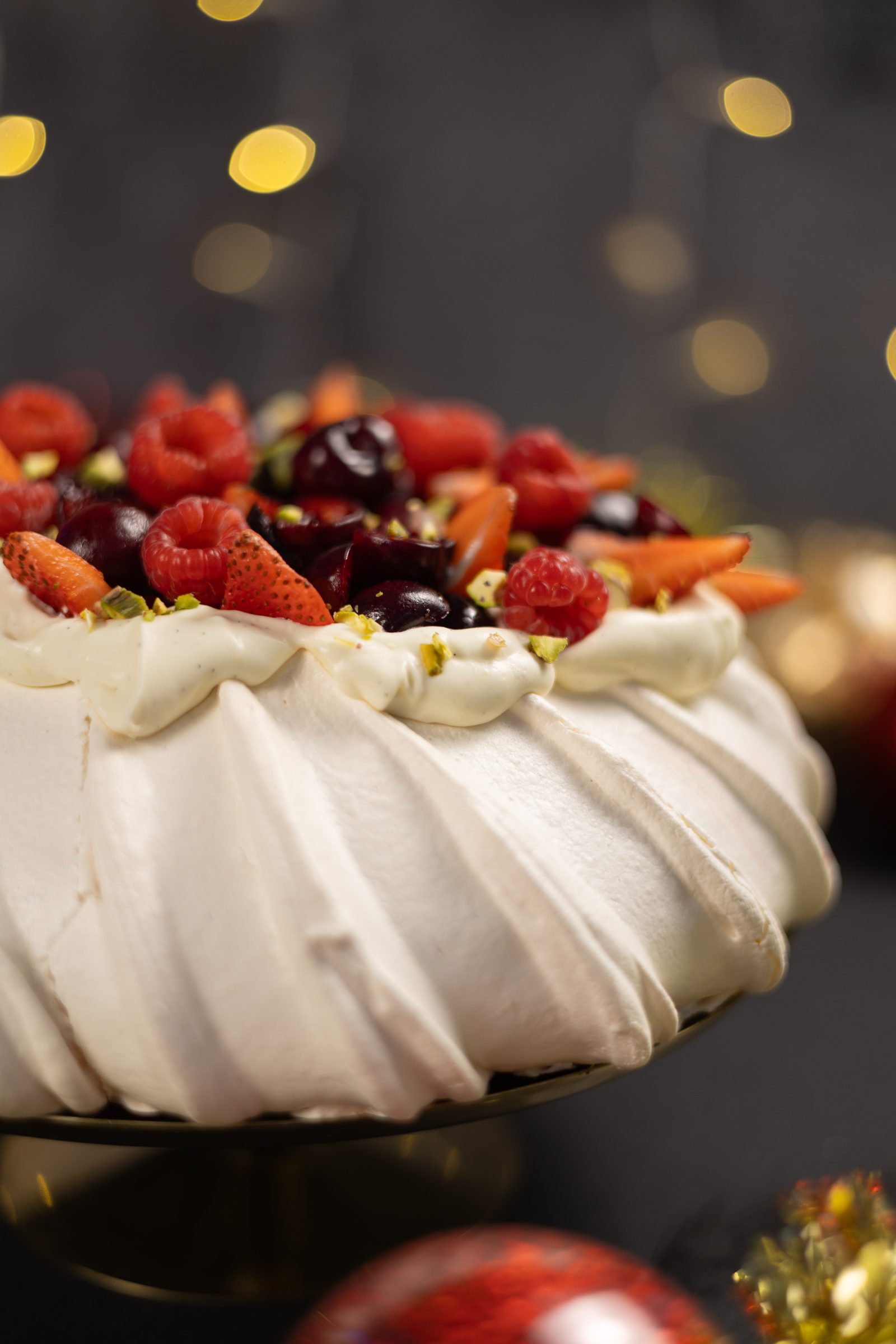 The ridged meringue sides and berry topping of a very berry pavlova, close up from the side