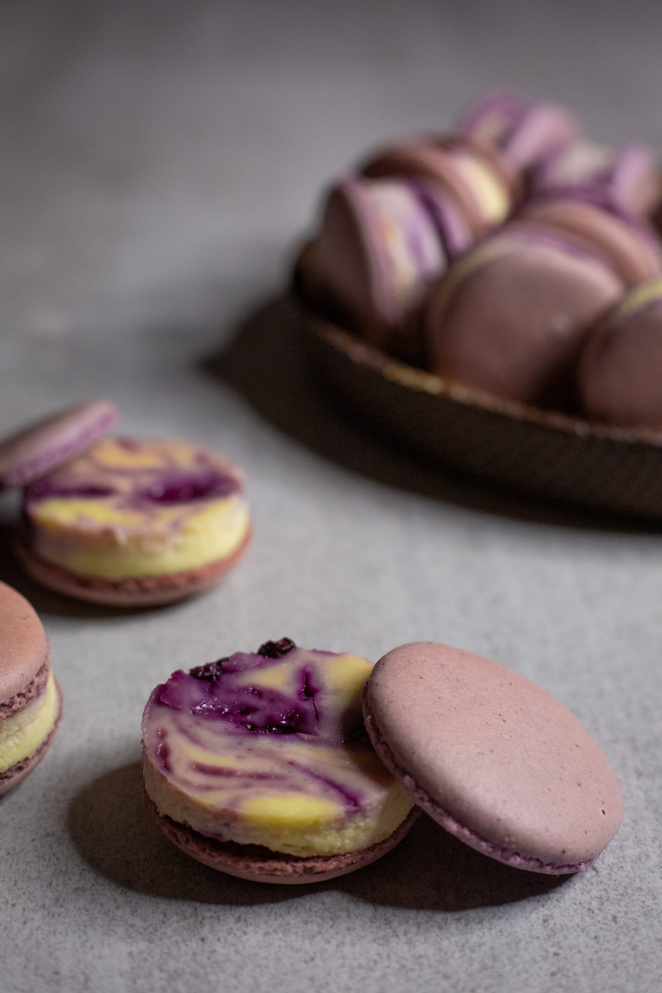 Blueberry cheesecake macarons showing their swirled filling, the plate behind