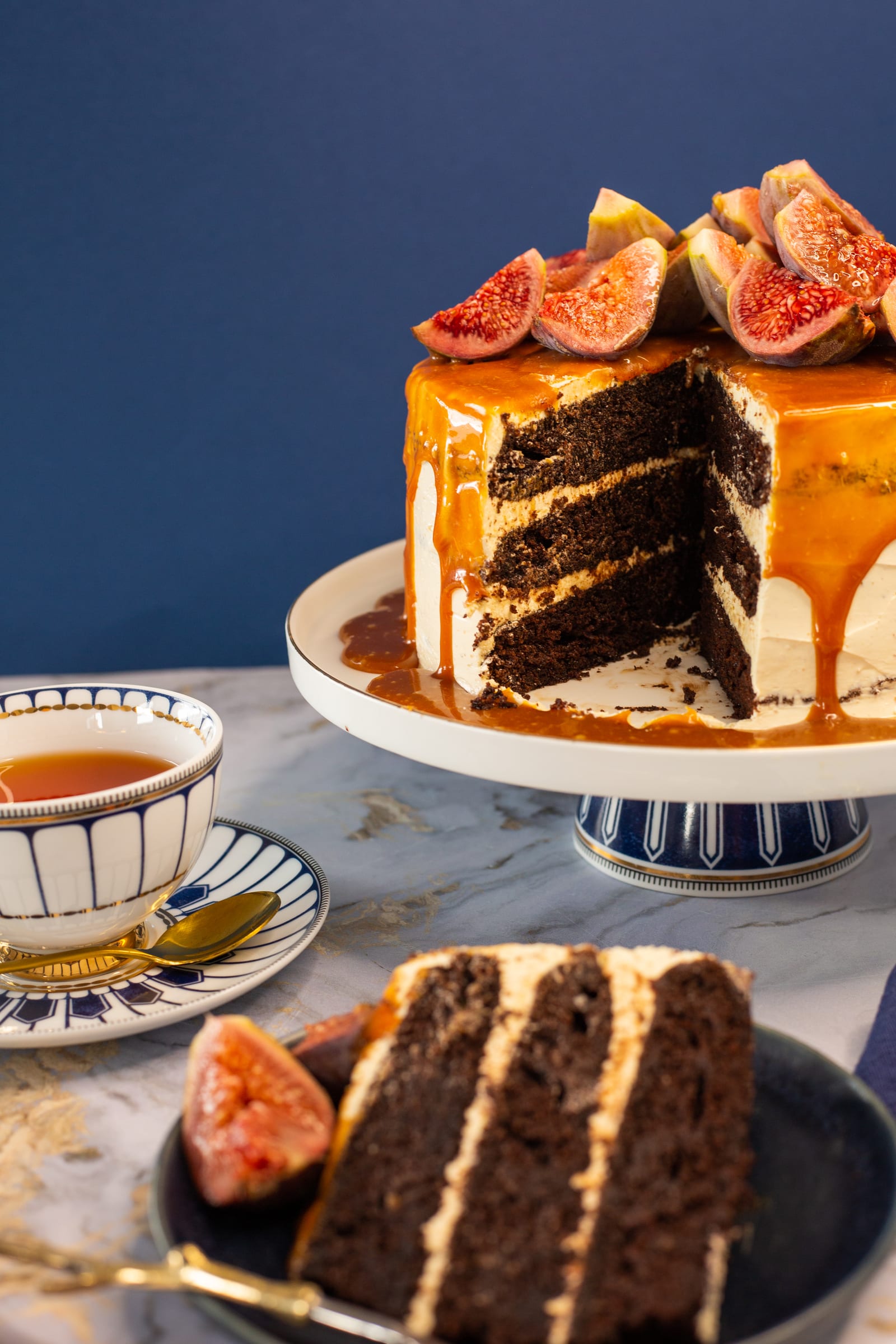 The cut devil's food cake on its stand showing dark chocolate layers, with a slice in front