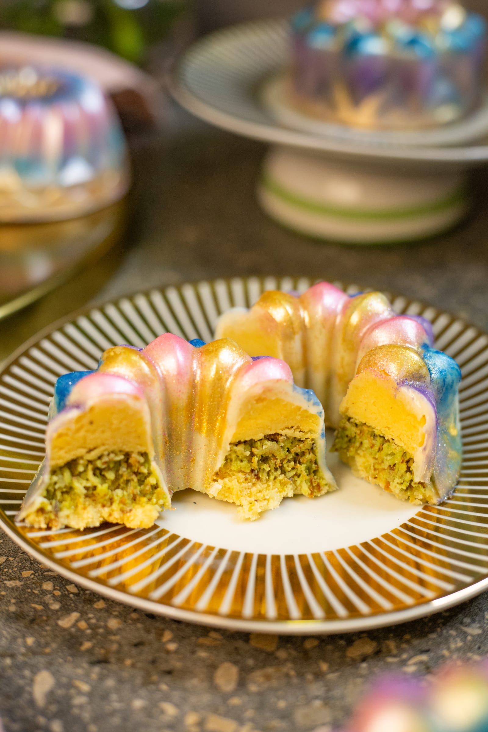 A Dubai pistachio burfee bundt cut open, showing the green pistachio kataifi filling inside the white chocolate shell