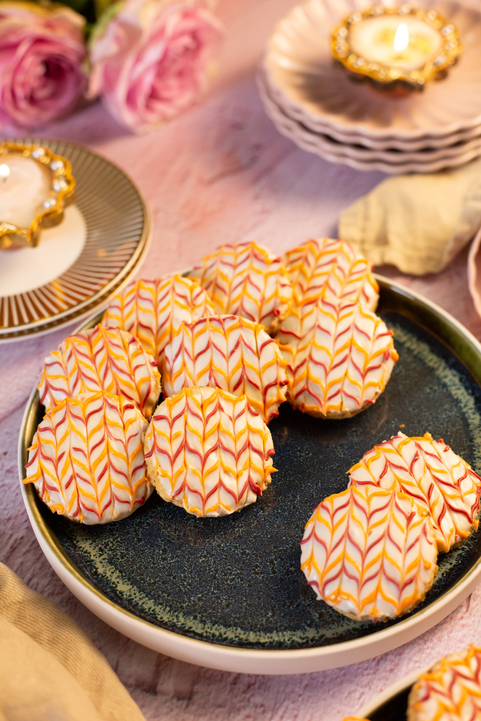 Iced biscuits on a dark plate, with roses behind