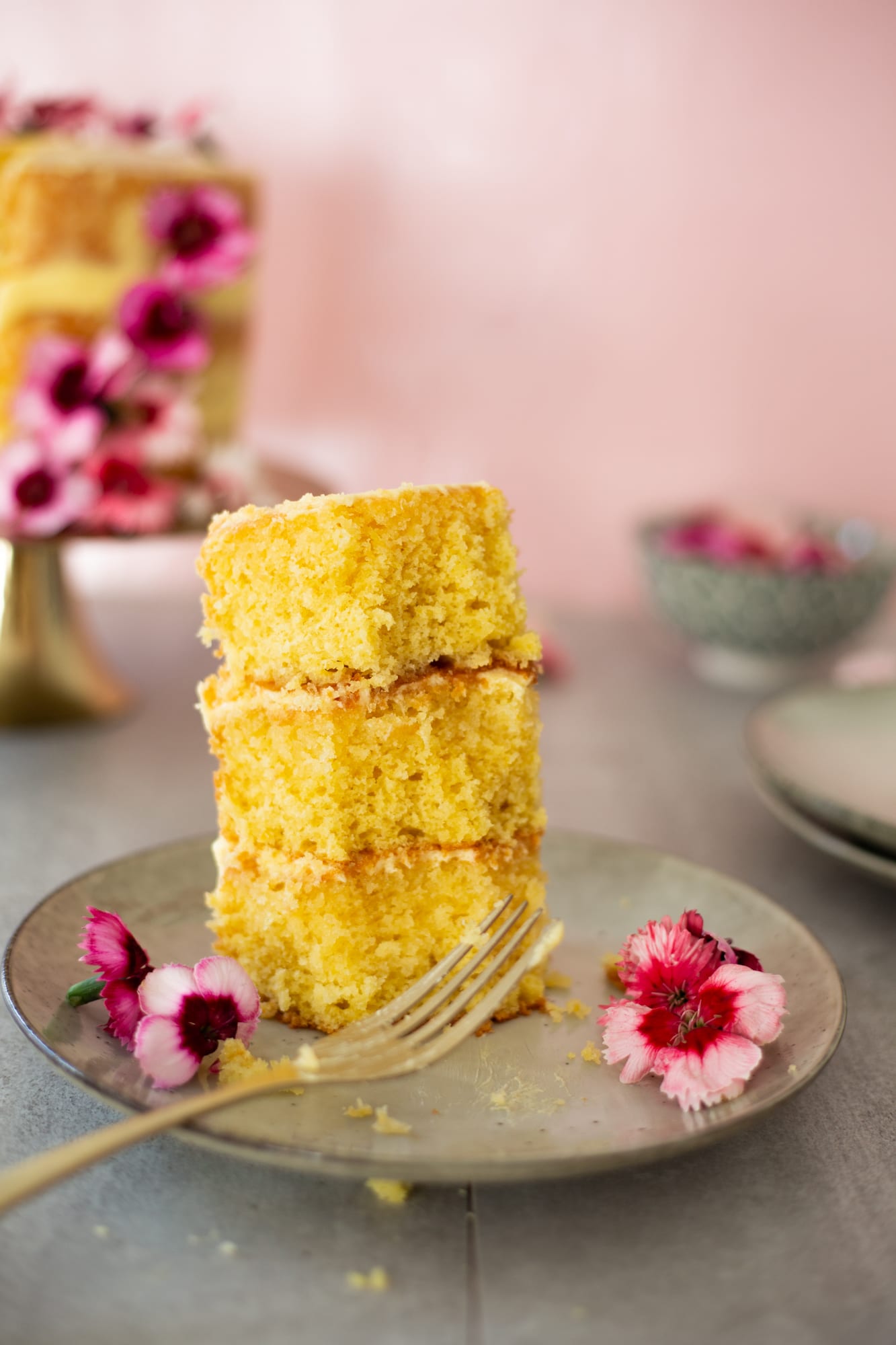 A slice of lemon curd cake with a bite taken out and a fork beside it