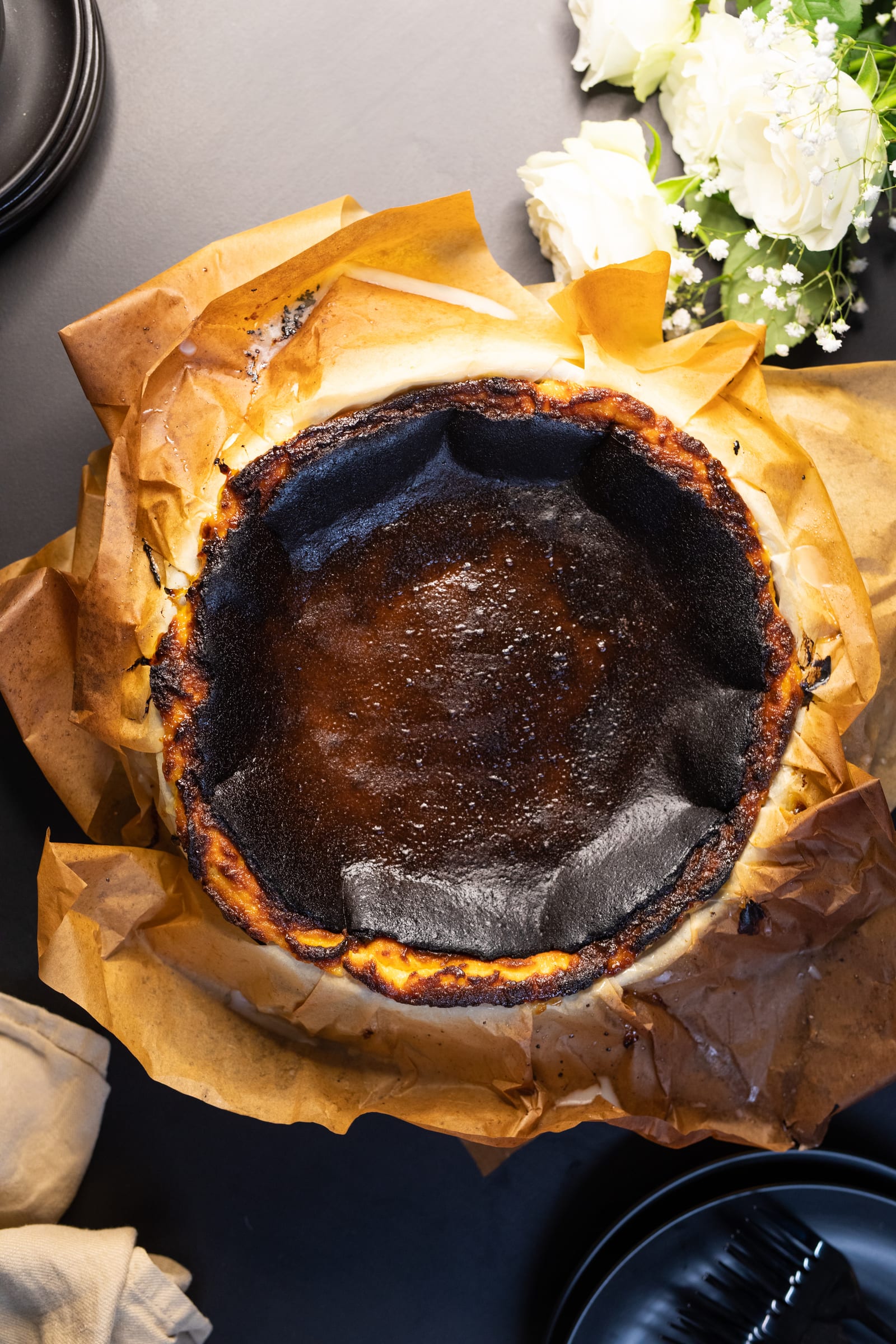 The burnt top of a Basque cheesecake from above, nestled in crinkled baking paper