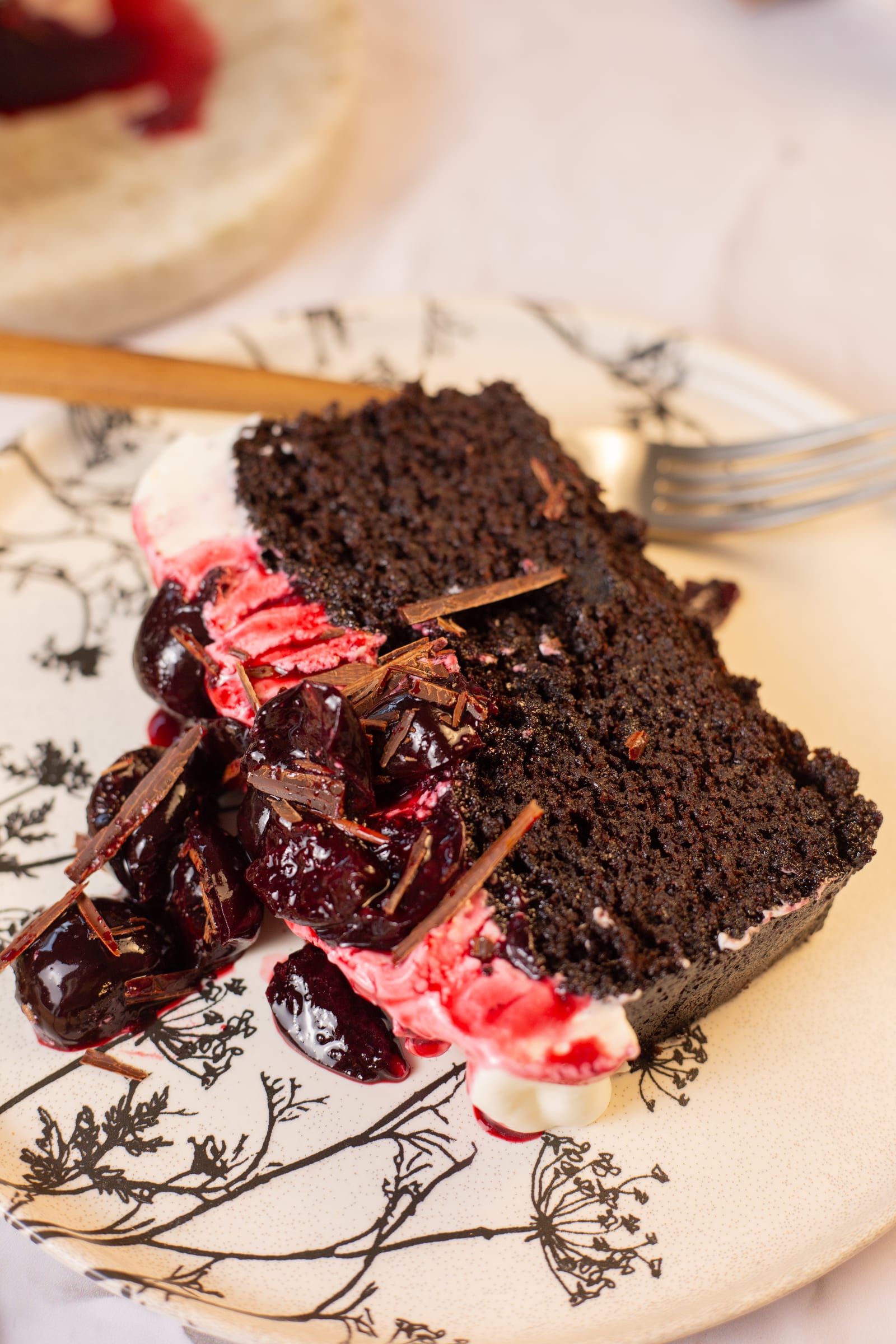 A slice of black forest loaf with cherries on a patterned plate