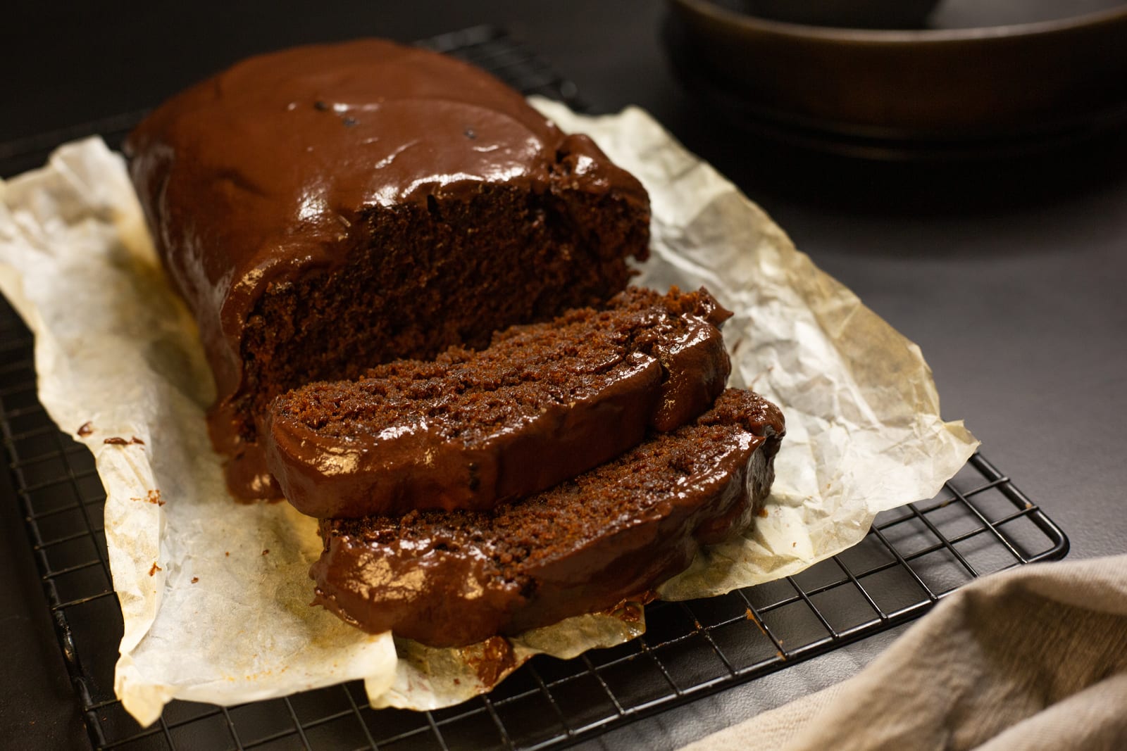 Chocolate banana bread with a glossy ganache top, cut into thick slices