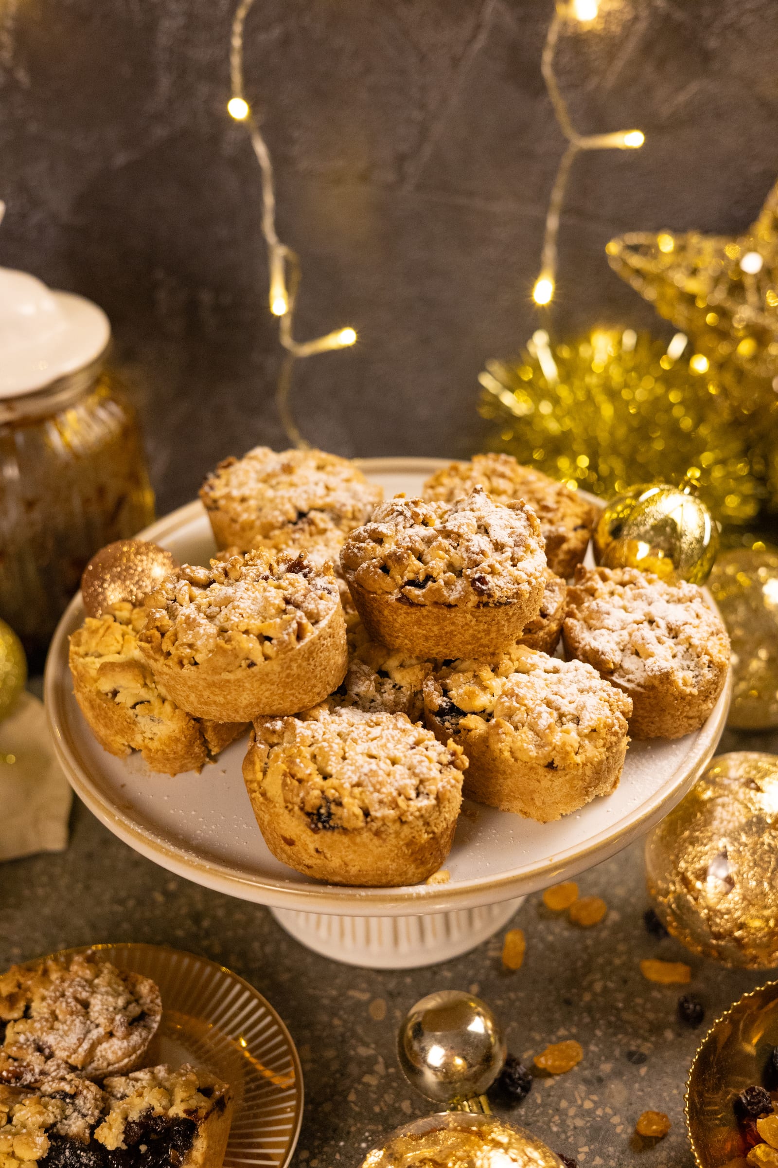 Fruit mince pies piled on a cake stand under fairy lights