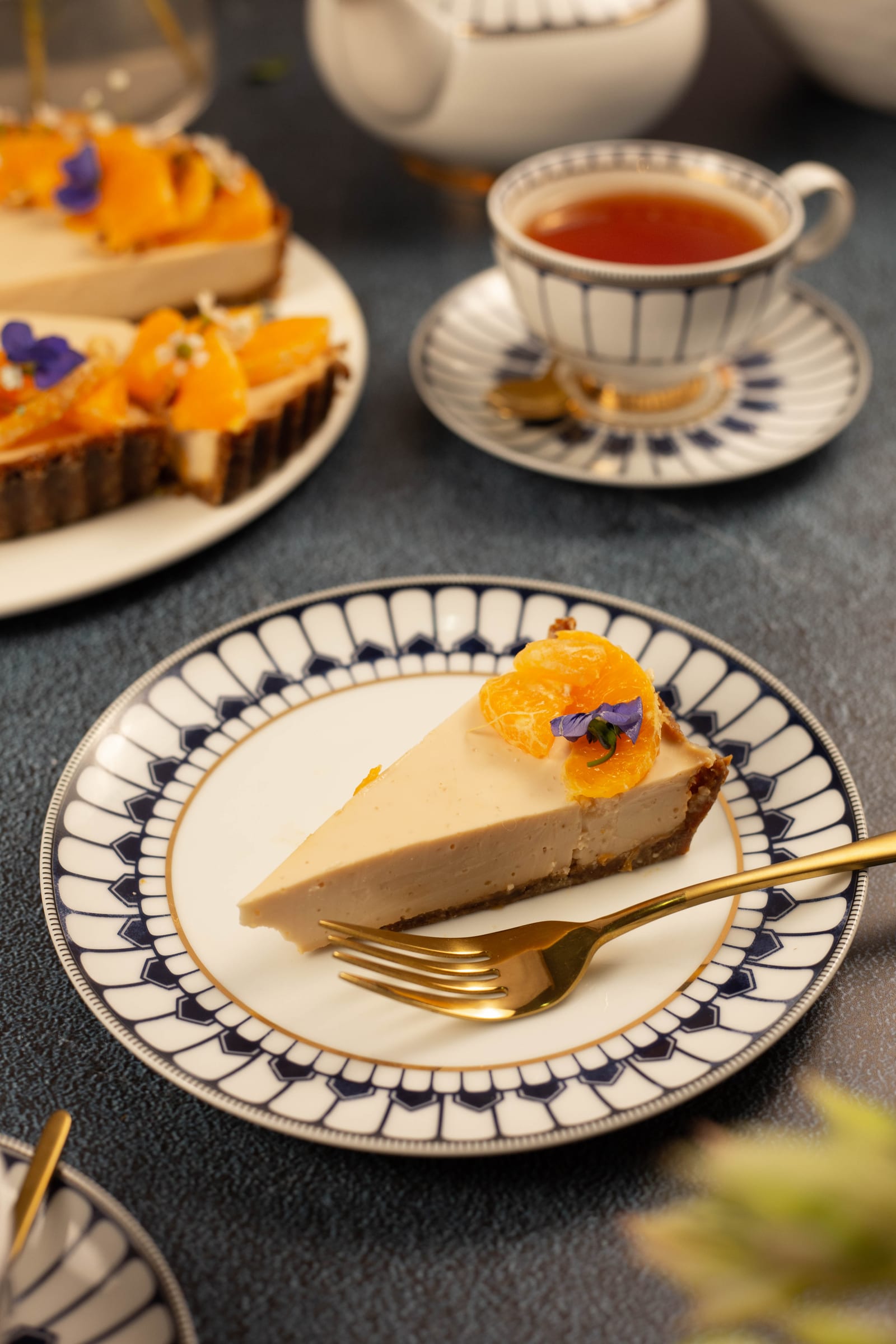 A slice of tart on a patterned plate with a gold fork