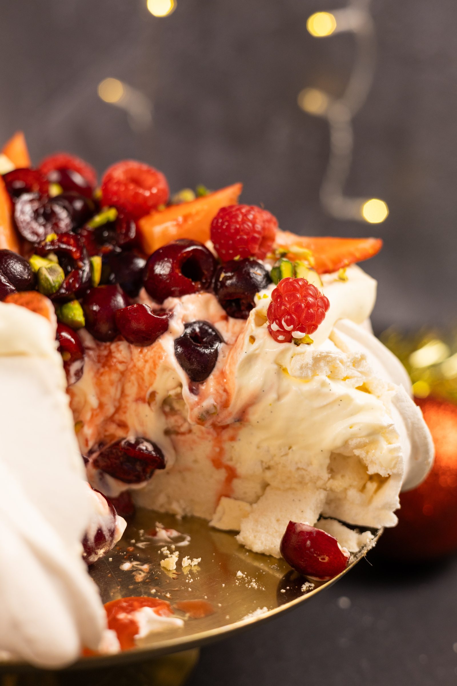 The soft marshmallowy centre and berry-streaked cream inside a cut very berry pavlova, from the side