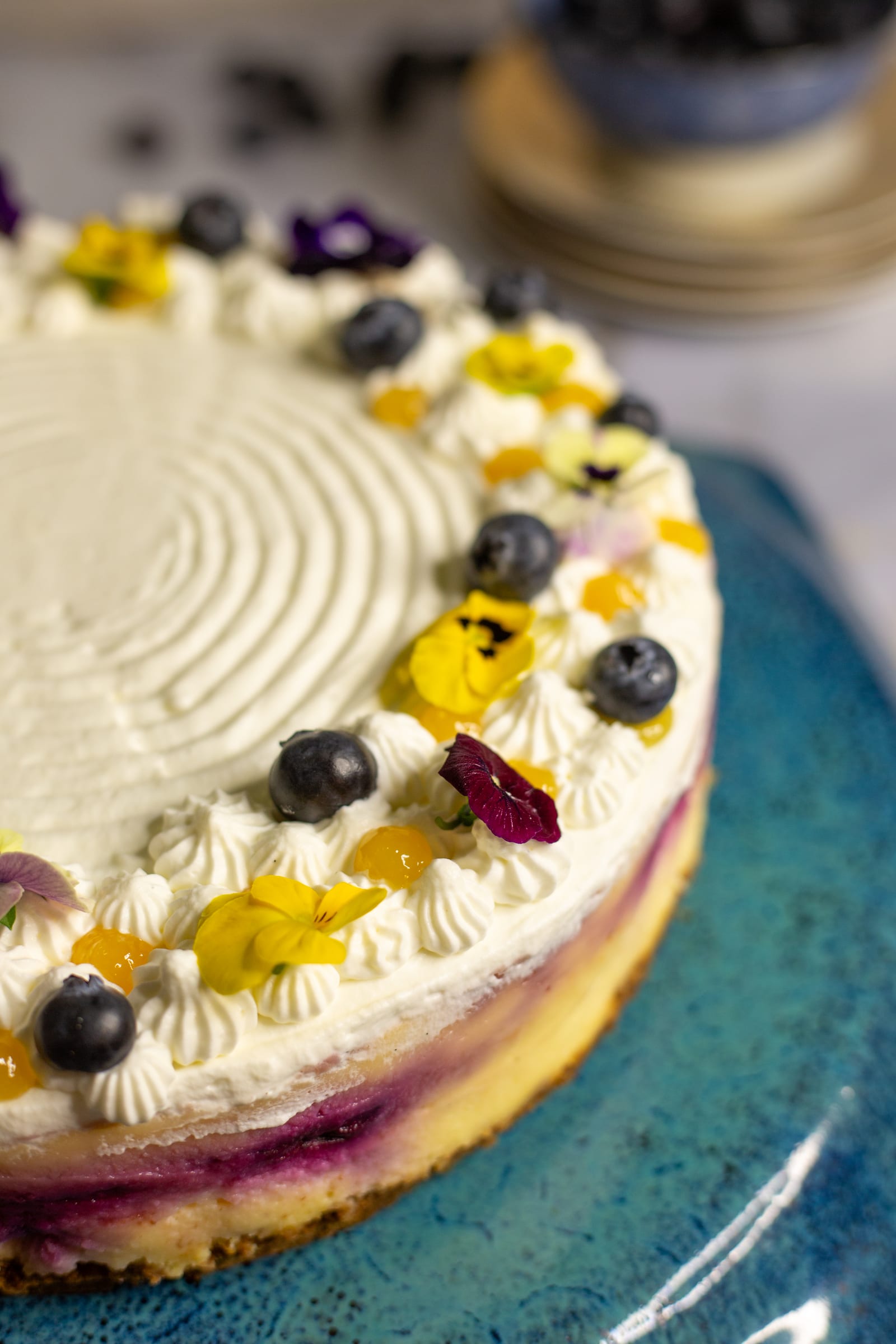 The side of the lemon and blueberry cheesecake, showing the blueberry swirl beneath the piped cream