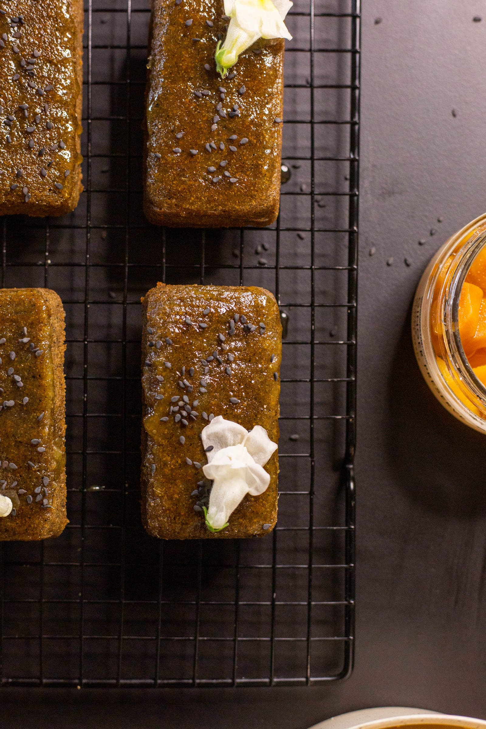 Close-up of black sesame and ginger financiers topped with cream, from above
