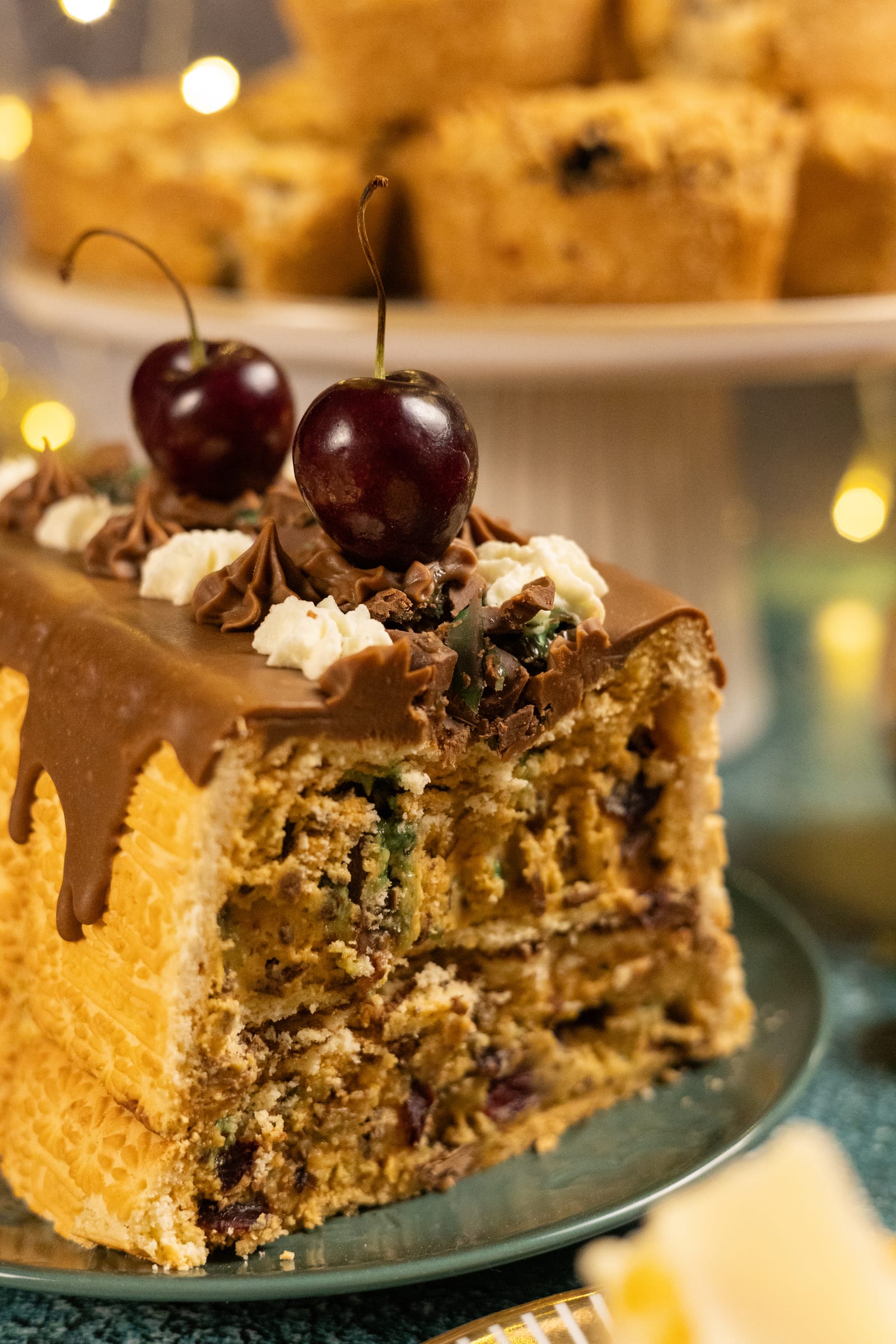 A slice of layered cake with cherries and chocolate drizzle