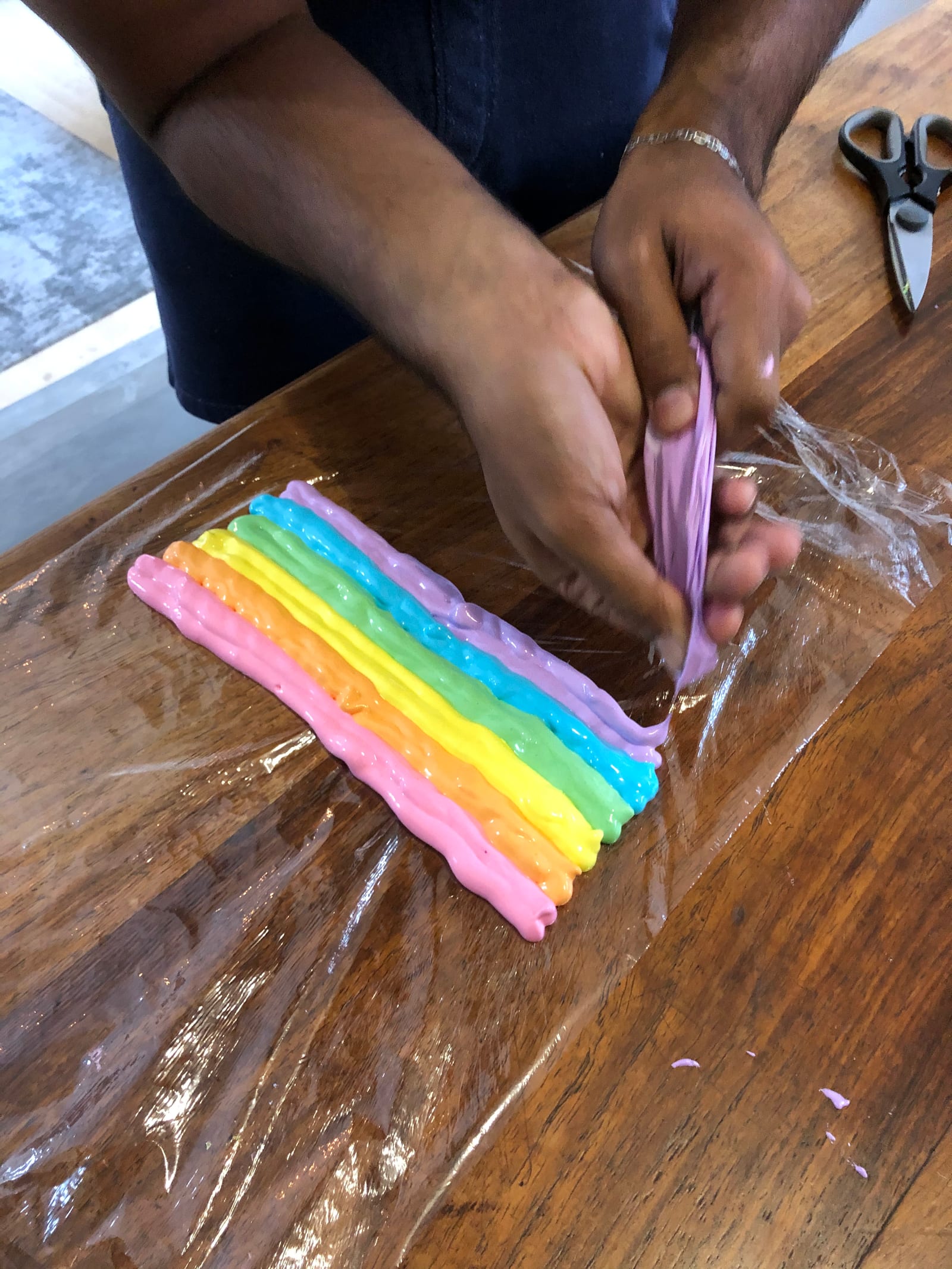 Stripes of coloured meringue being laid on cling wrap to fill the piping bag, from above