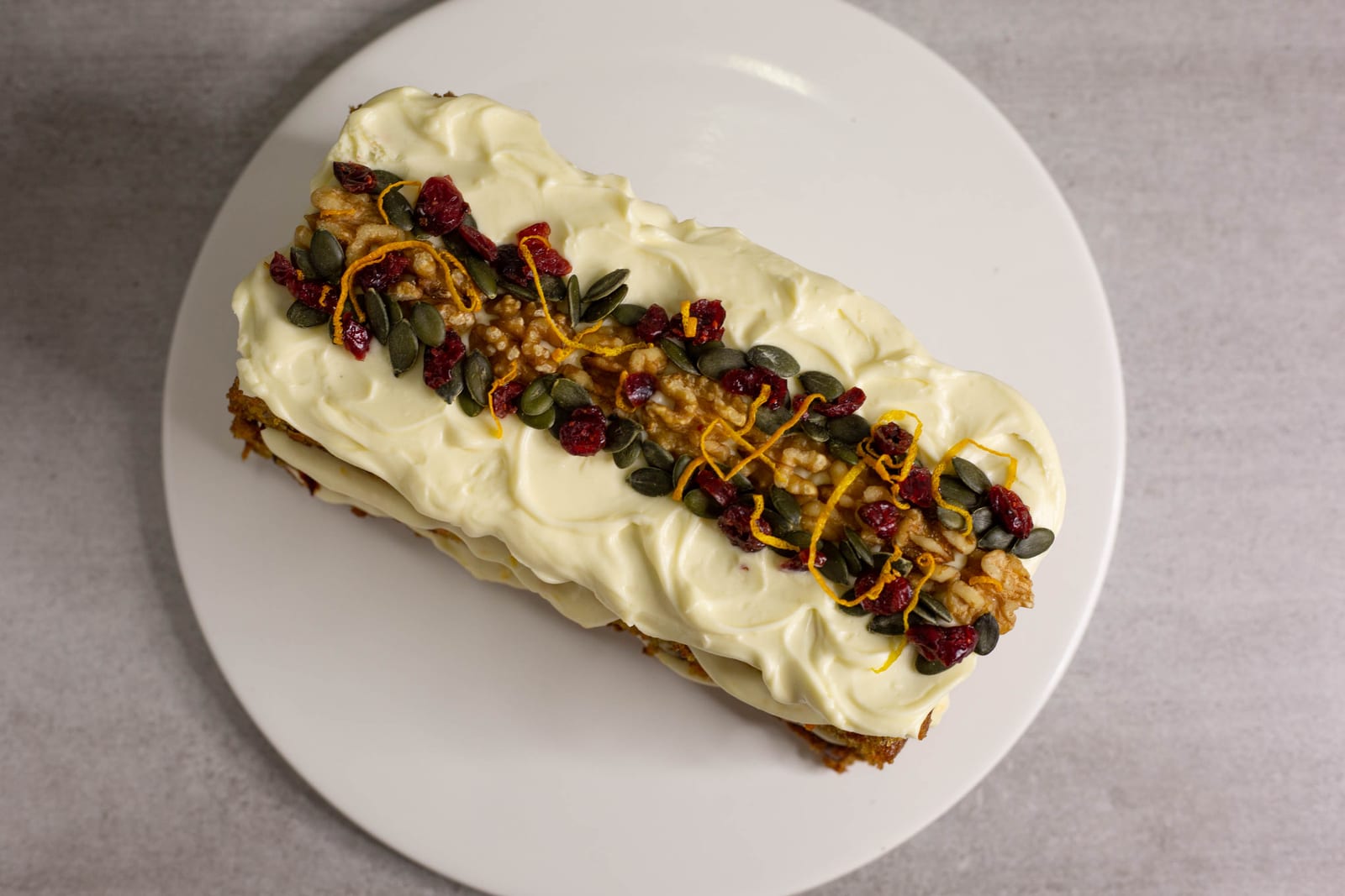 The whole rectangular carrot cake on a round white plate, from above