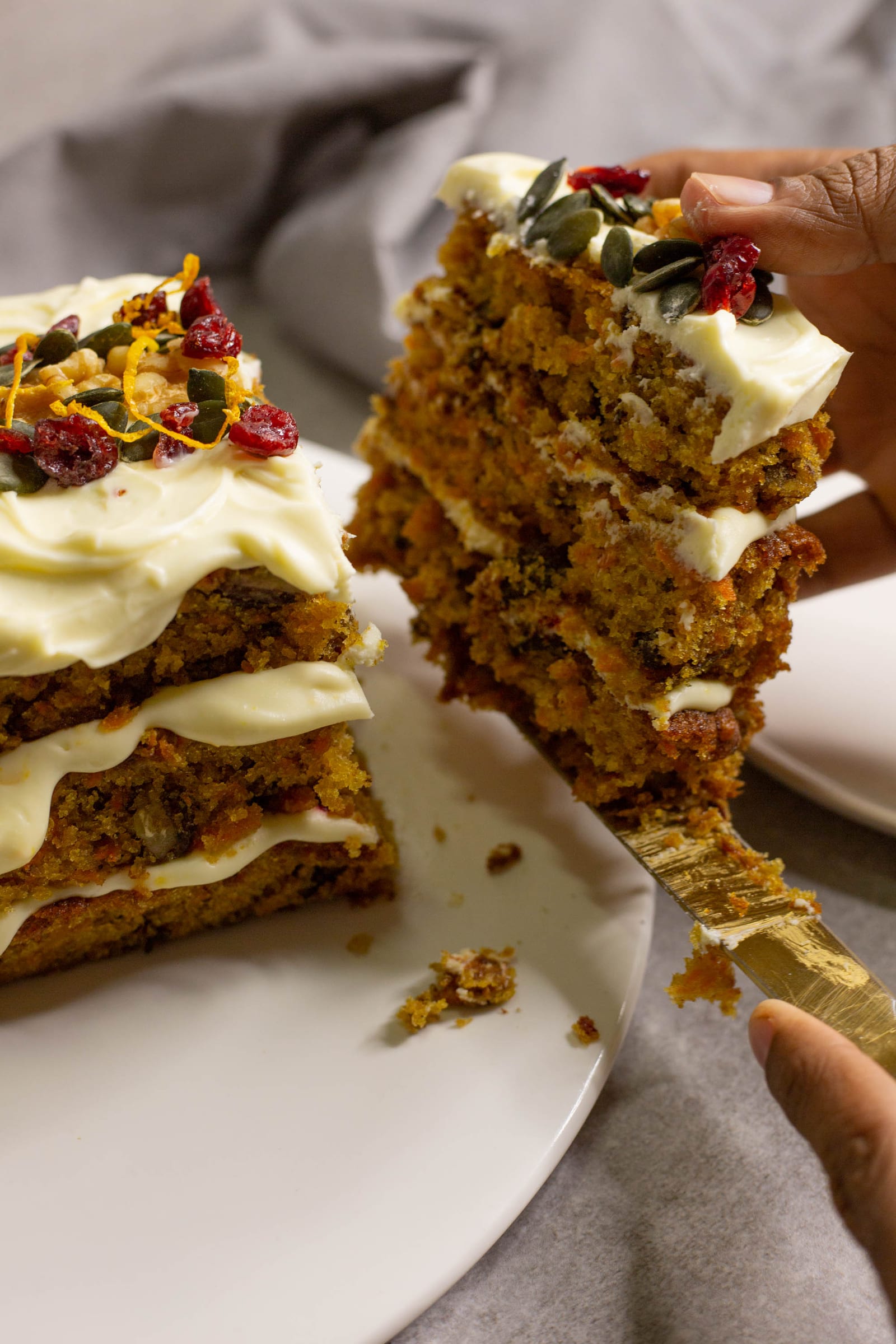 A slice of carrot cake being lifted away, showing its spiced layers and icing