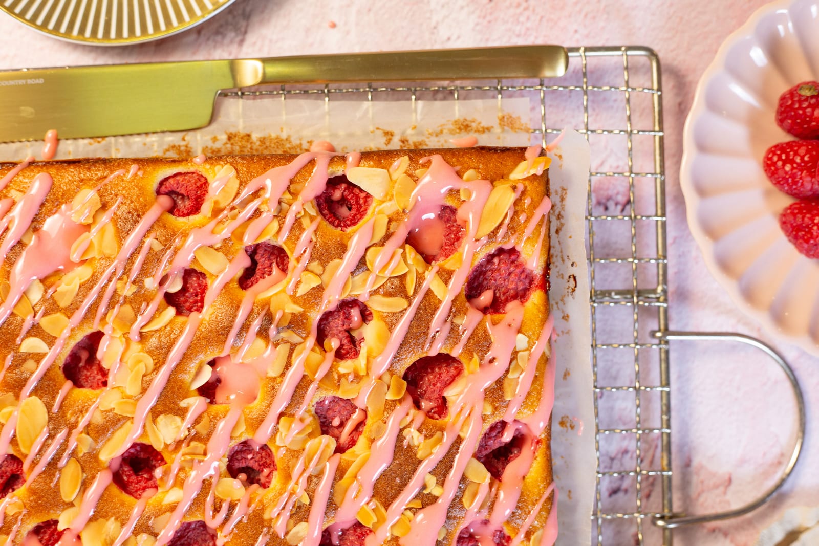 The drizzled snack cake on a wire rack, with a gold knife