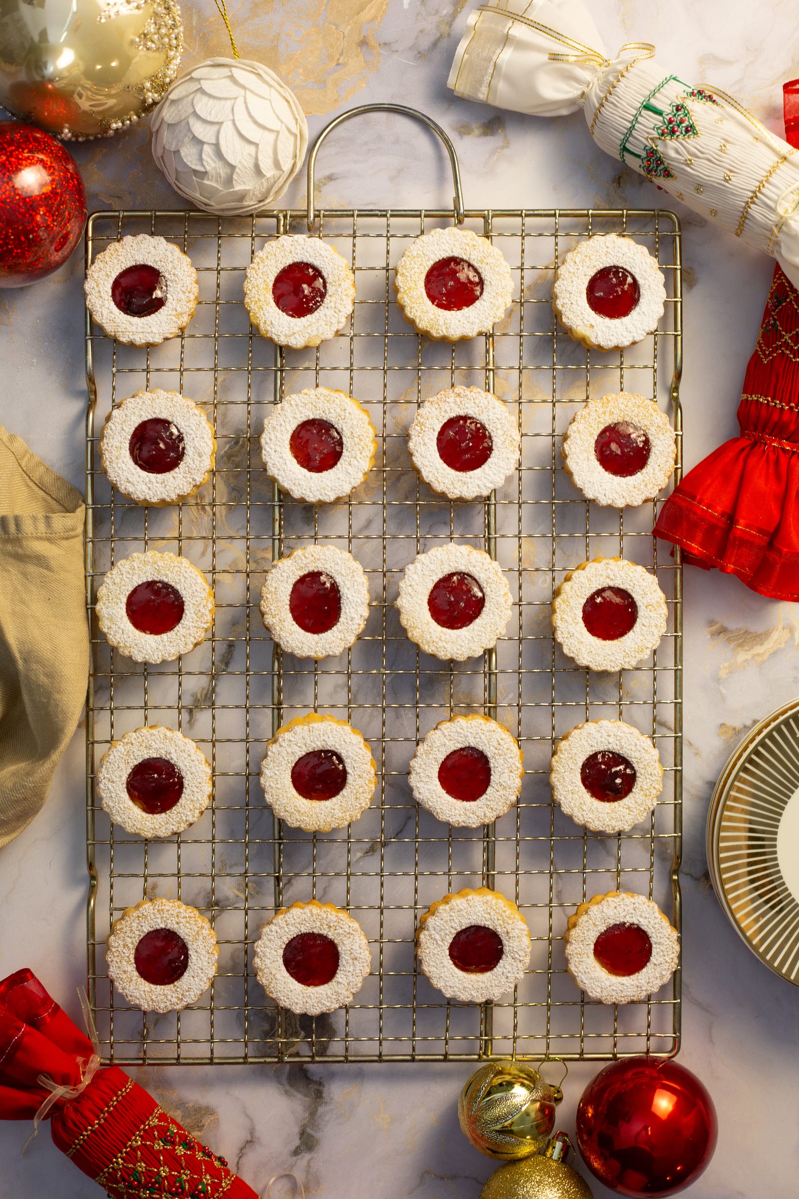 Rows of round lemon and raspberry Linzer cookies on a wire rack, seen from above
